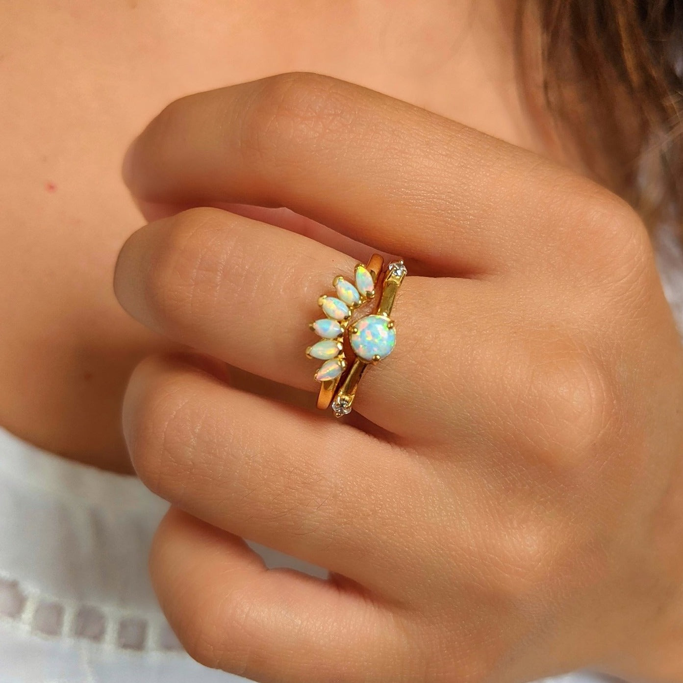 Gold-plated ring set featuring a round opal center stone and a curved crown of marquise opals, styled on a hand with natural lighting.