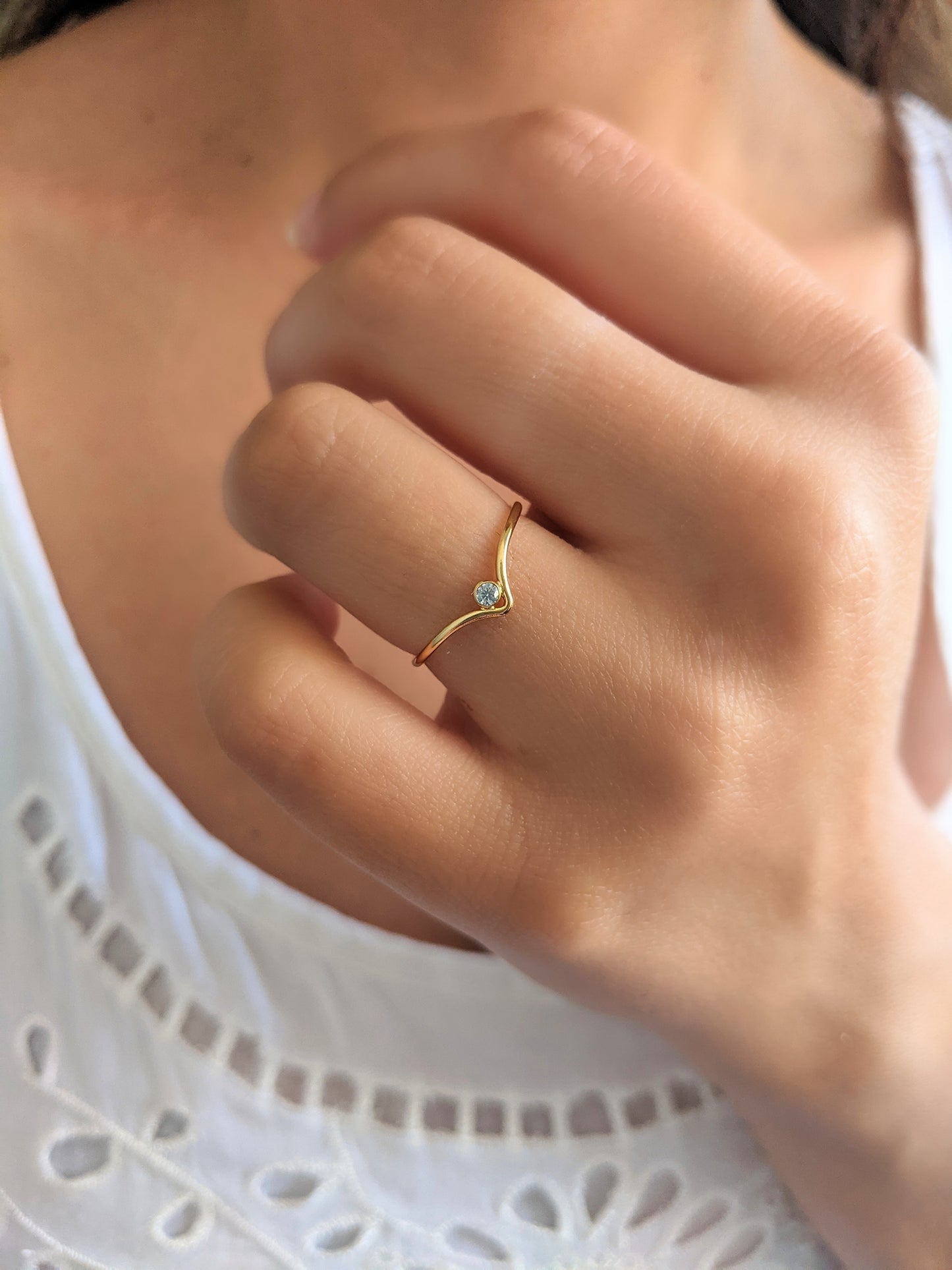 Gold-filled "v" stacking ring with a tiny cubic zirconia, worn on the ring finger.