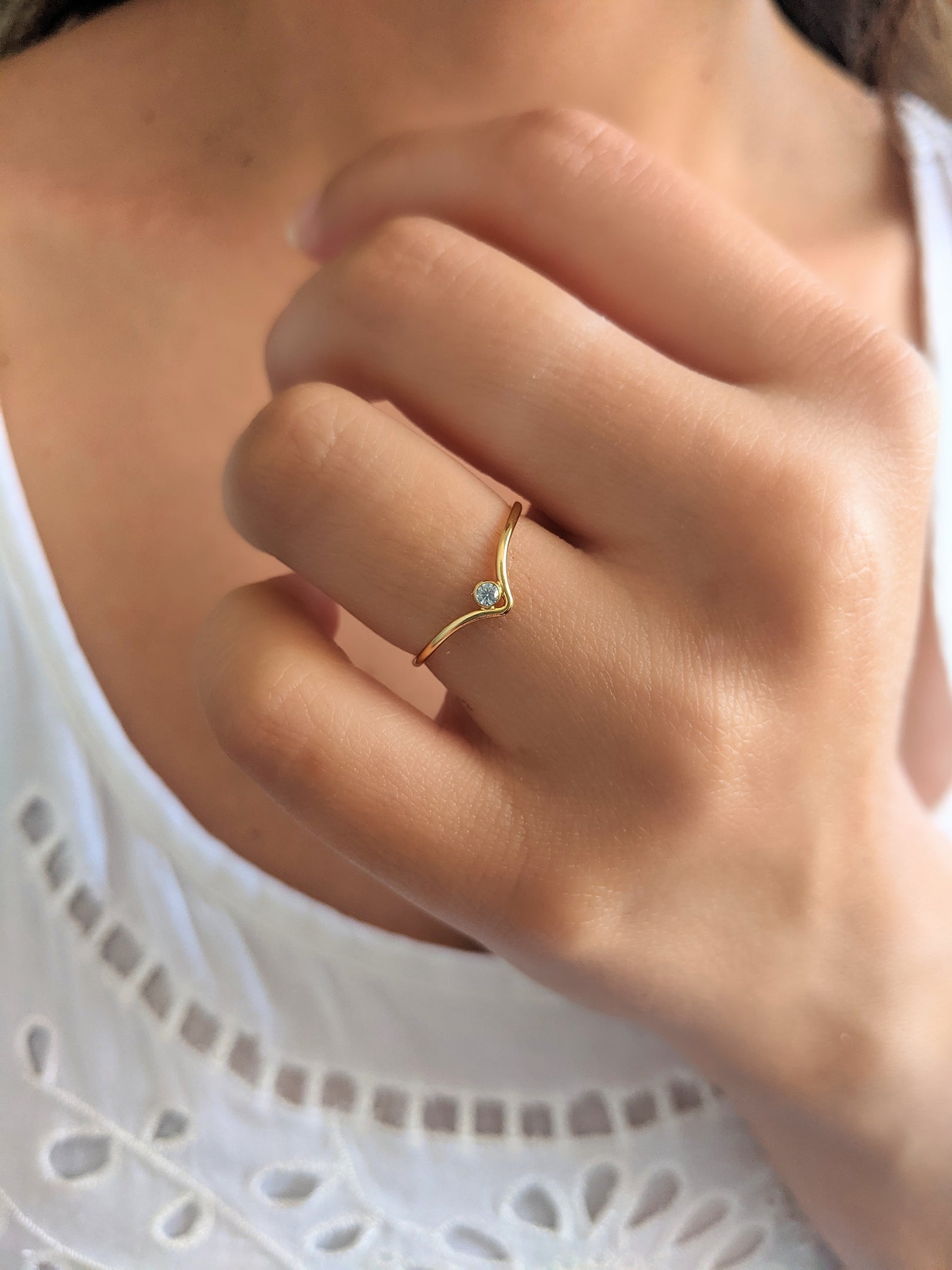 Gold-filled "v" stacking ring with a tiny cubic zirconia, worn on the ring finger.