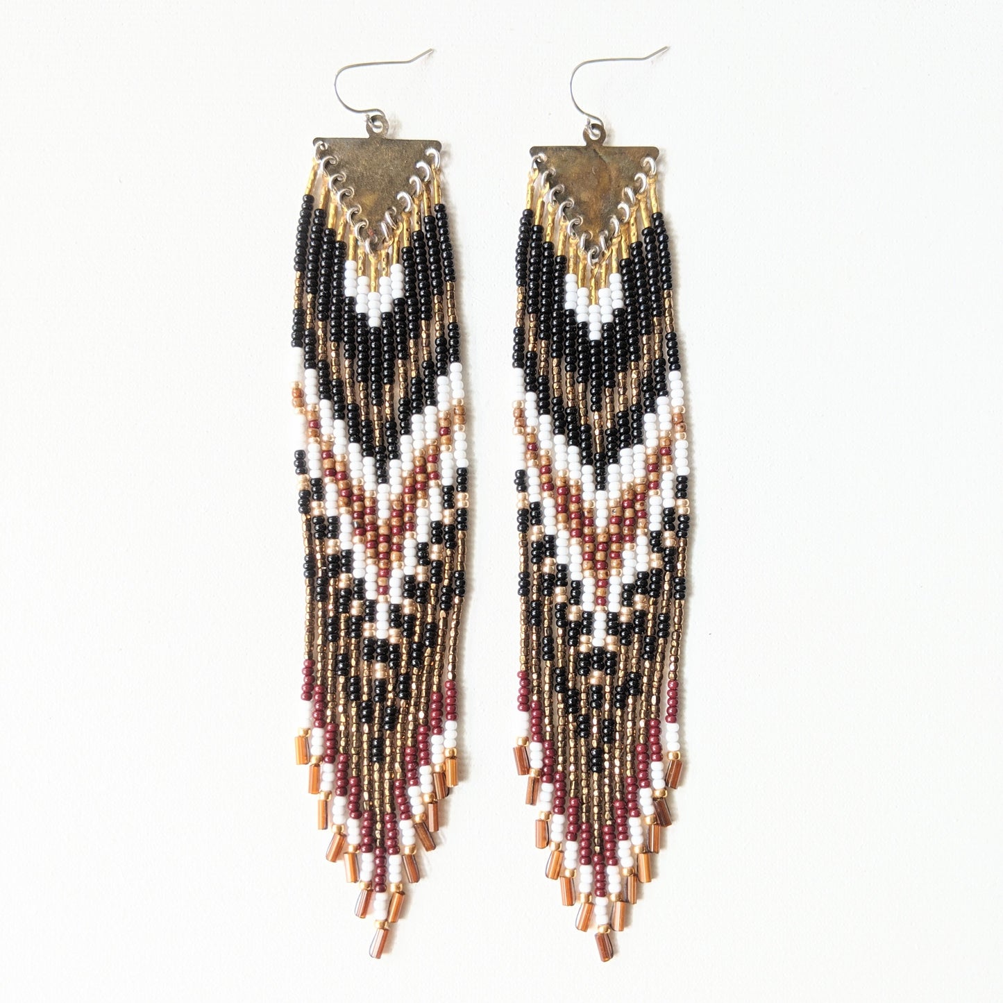 Artistic long native earrings from Moon & Milk with black, white, gold, and wine red beads. Handcrafted beadwork meets geometric brass jewelry design.