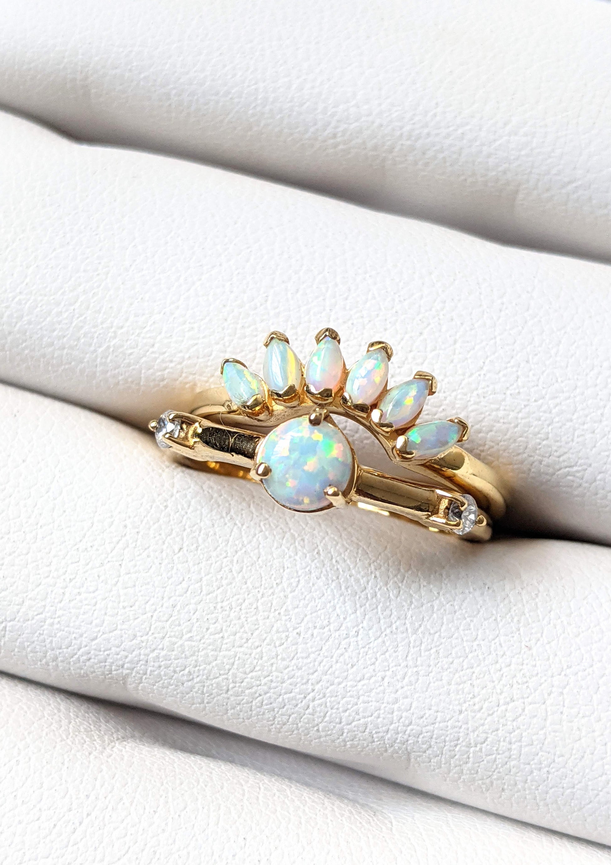 Gold-plated ring set featuring a round opal center stone and a curved crown of marquise opals, styled on a soft white ring display.