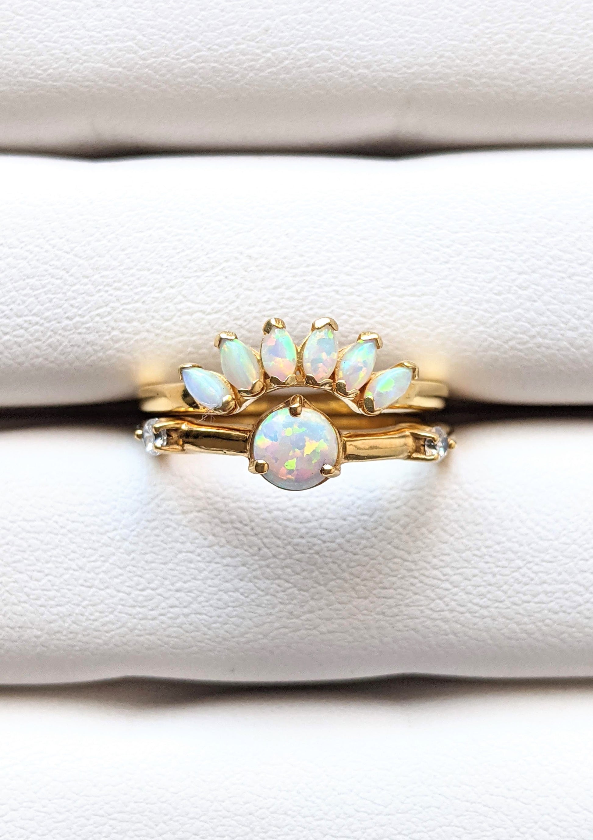 Gold-plated ring set featuring a round opal center stone and a curved crown of marquise opals, styled on a soft white ring display.