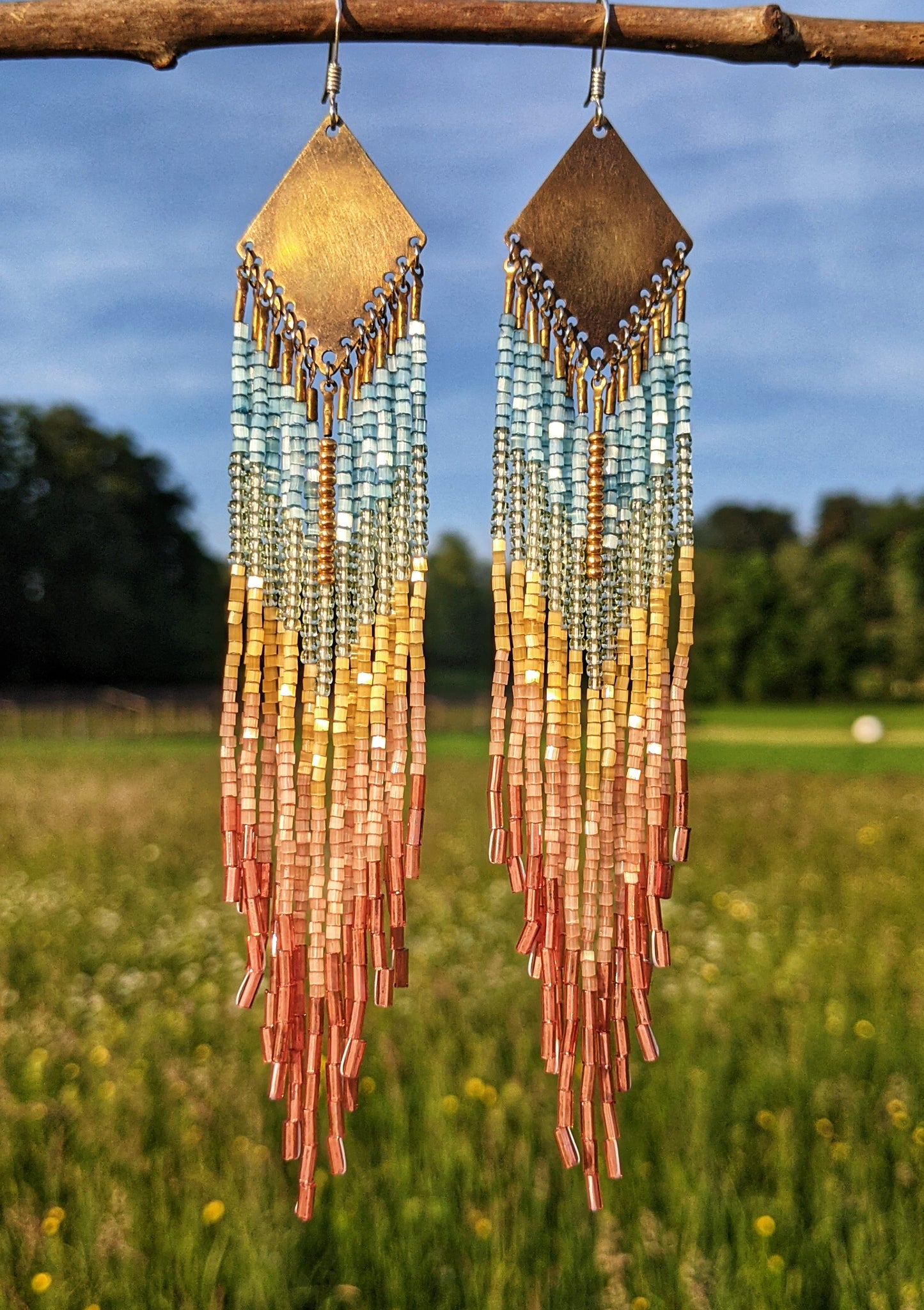 Moon & Milk handcrafted earrings with Czech hex-cut beads in soft blue, yellow, and coral tones, inspired by Venice Beach. Long fringe with brass tops.