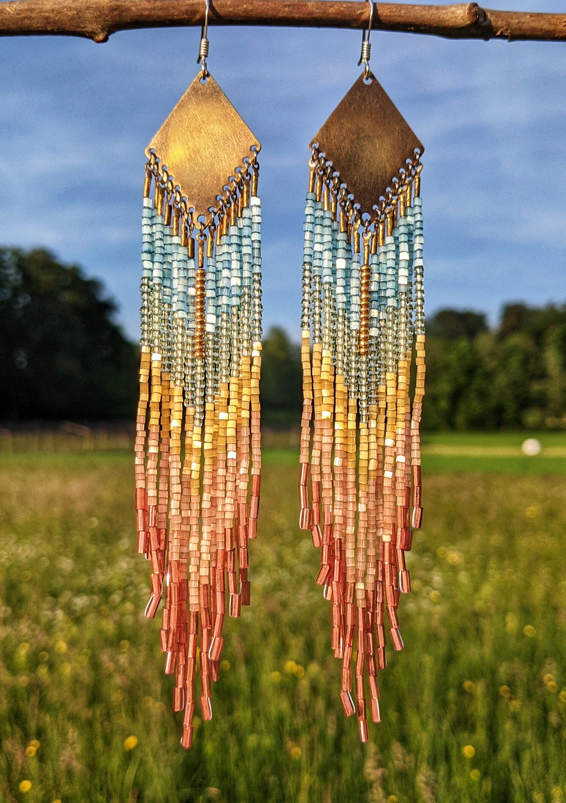 Moon & Milk handcrafted earrings with Czech hex-cut beads in soft blue, yellow, and coral tones, inspired by Venice Beach. Long fringe with brass tops.