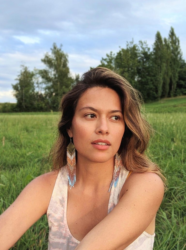 Woman wearing Moon & Milk's artisan earrings handcrafted with satin hex-cut beads, brass, and sterling silver. Soft pastel beadwork in a long native earring design.