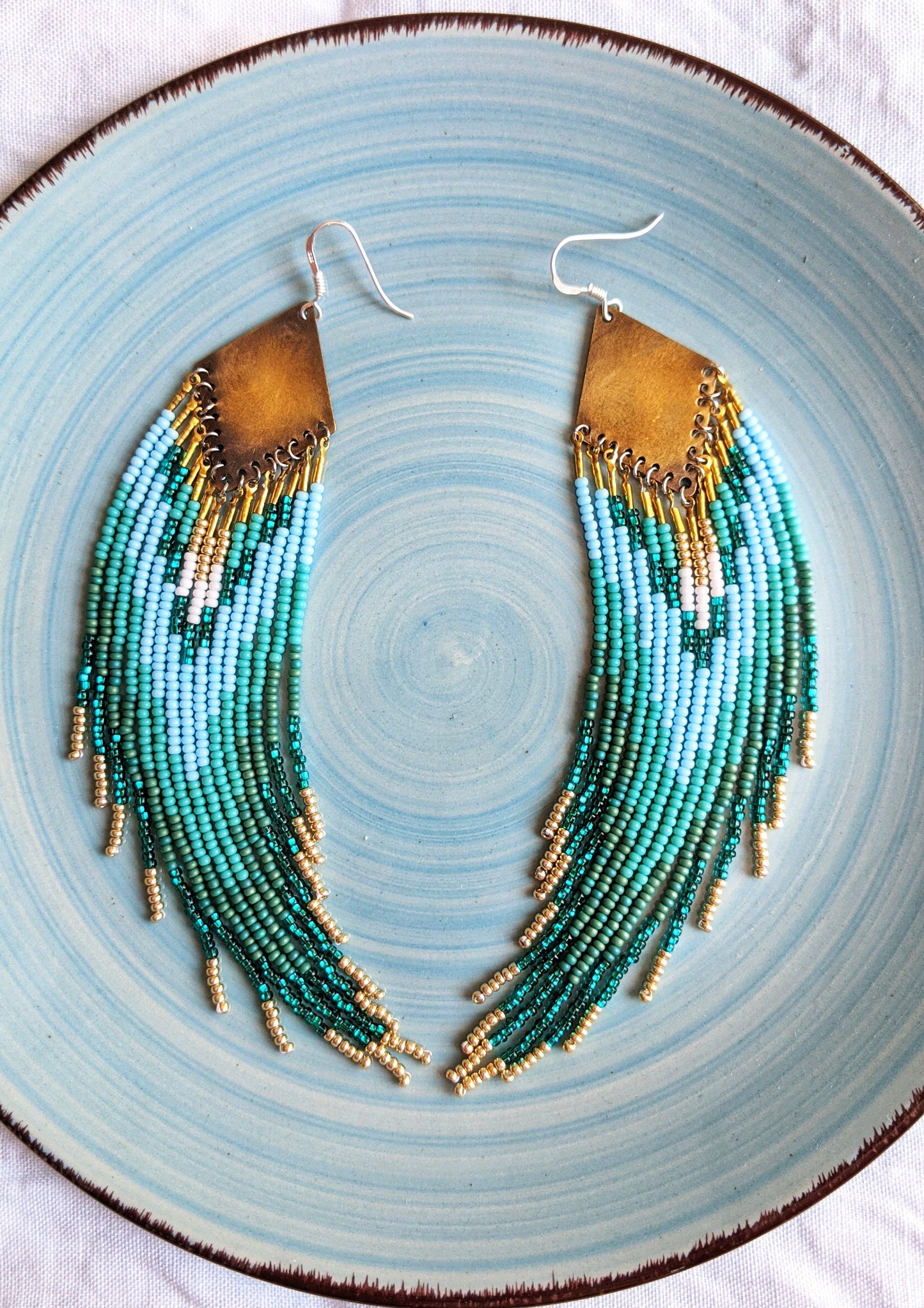 Handcrafted beaded earrings by Moon & Milk featuring cascading turquoise, sea green, and gold strands, inspired by the landscapes of Switzerland.