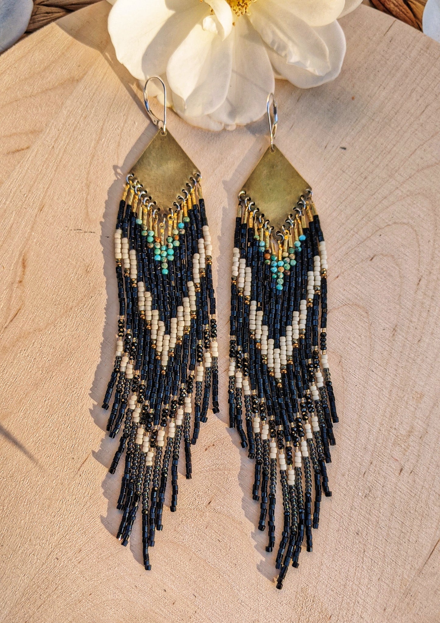 Long native beaded earrings in black, cream, and turquoise stones with brass tops, handcrafted for lovers of artisan jewelry and wearable art by Moon & Milk.