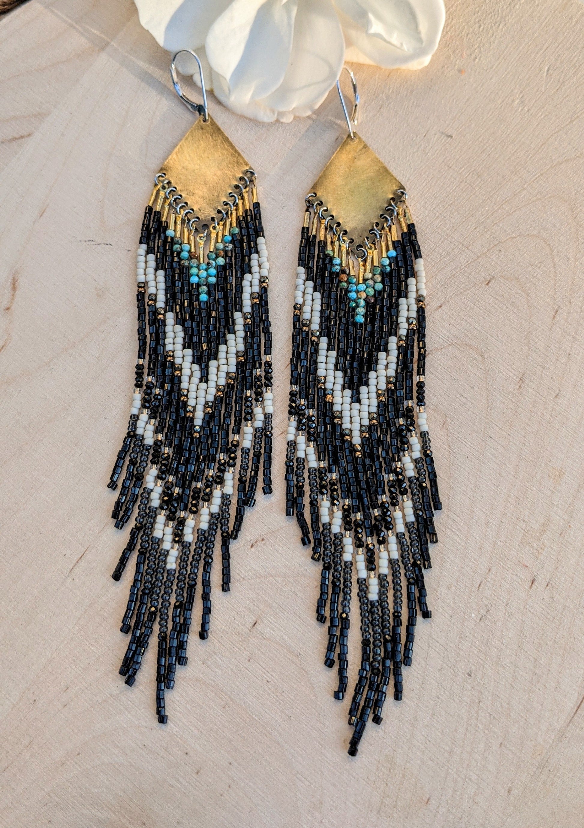 Long native beaded earrings in black, cream, and turquoise stones with brass tops, handcrafted for lovers of artisan jewelry and wearable art by Moon & Milk.