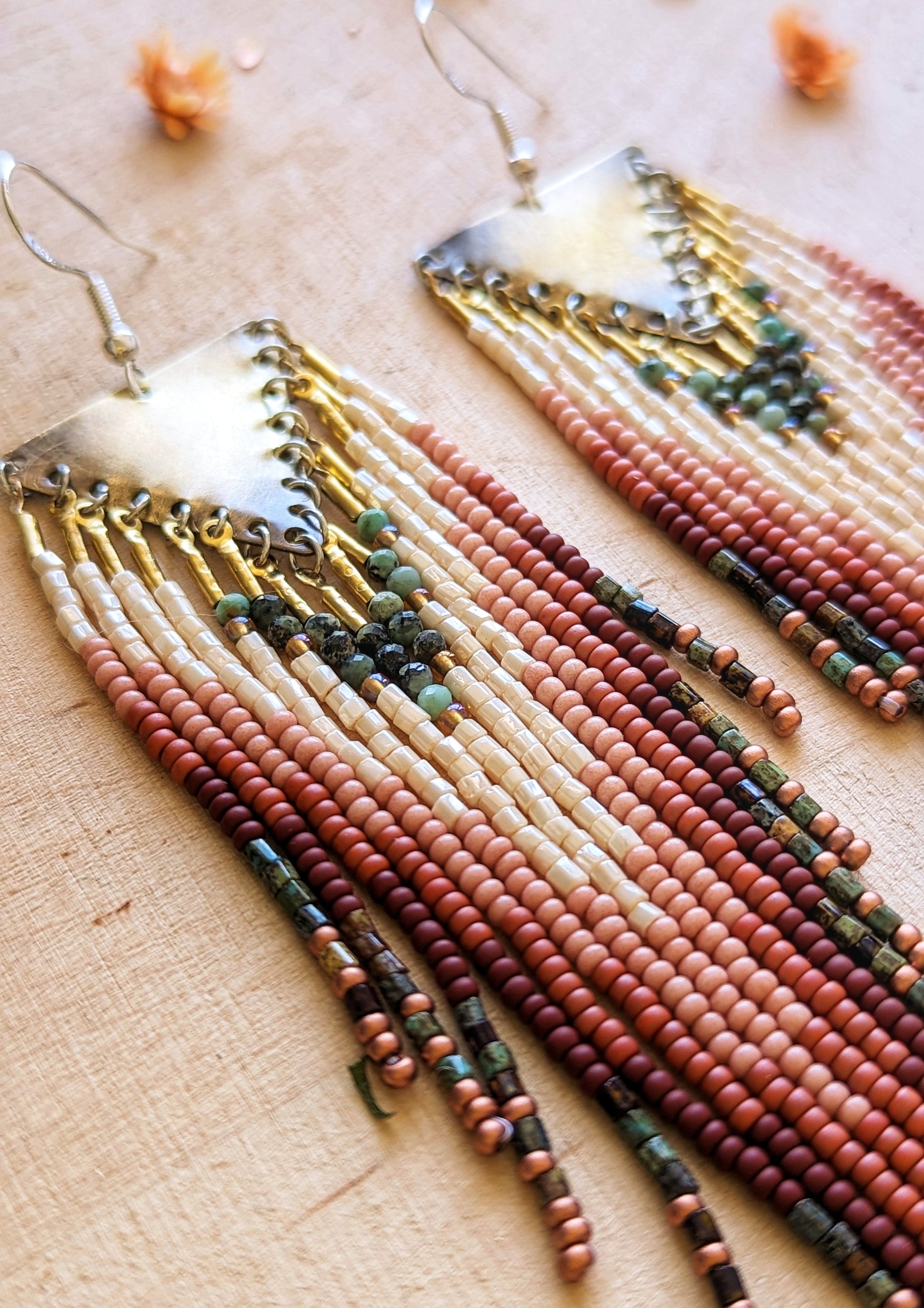 Moon & Milk beaded earrings featuring ivory, rust, pink, turquoise, and brown beaded fringes with brass triangle tops, inspired by wild desert blooms and earthy tones.