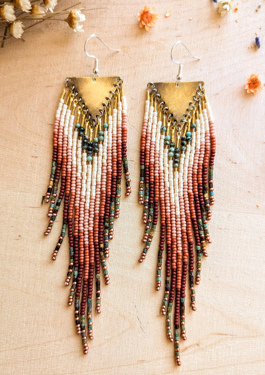 Moon & Milk earrings featuring ivory, rust, pink, turquoise, and brown beaded fringes with brass triangle tops, inspired by wild desert blooms and earthy tones.