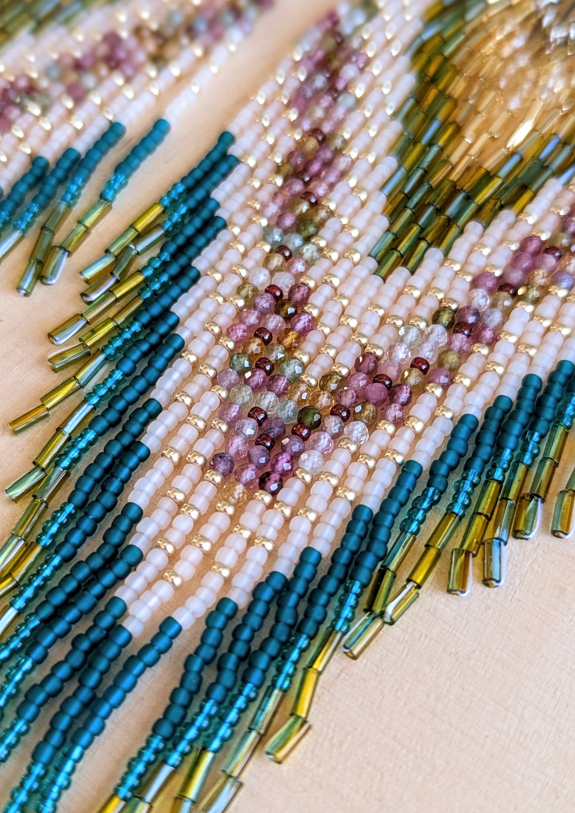 Close-up of Moon & Milk’s Xochipilli earrings showing gold, olive, water tourmaline, and blush bead strands.