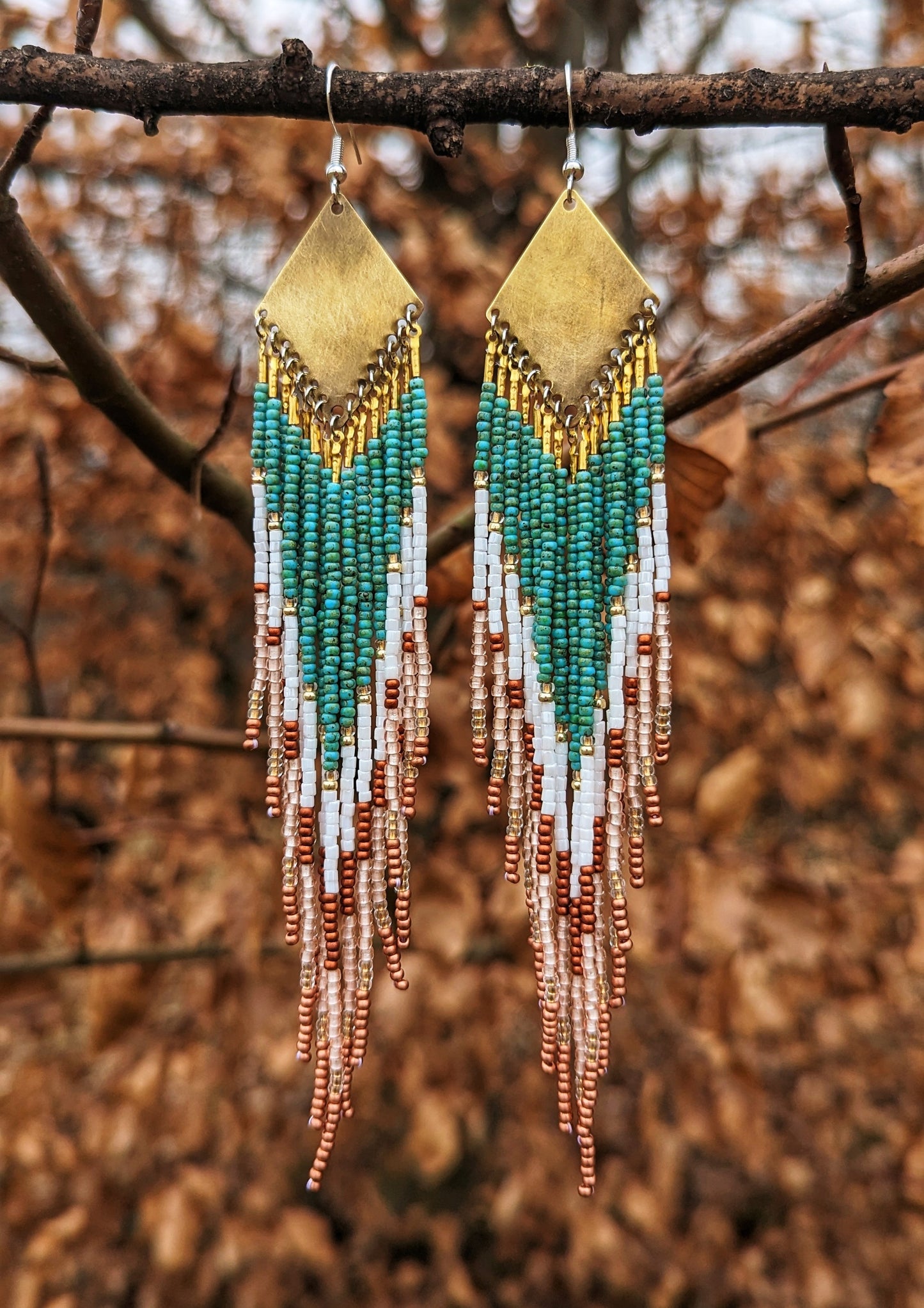 Handcrafted Moon & Milk earrings with turquoise, white, and crimson beads arranged in a chevron pattern, hanging from brass diamond-shaped findings.