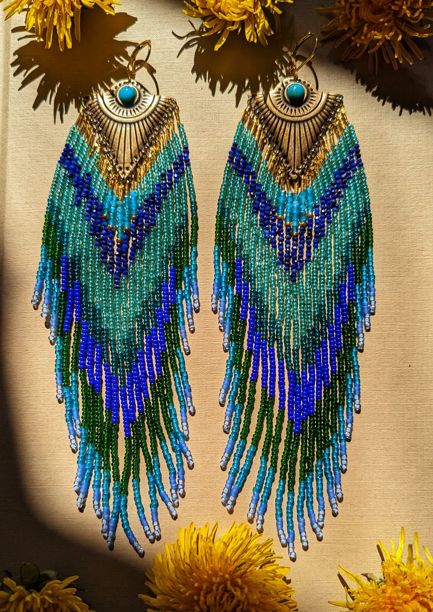 Handcrafted beaded earrings by Moon & Milk inspired by Huitzilopochtli, featuring apatite, lapis lazuli stones, and turquoise cabochons, designed to mimic a hummingbird.