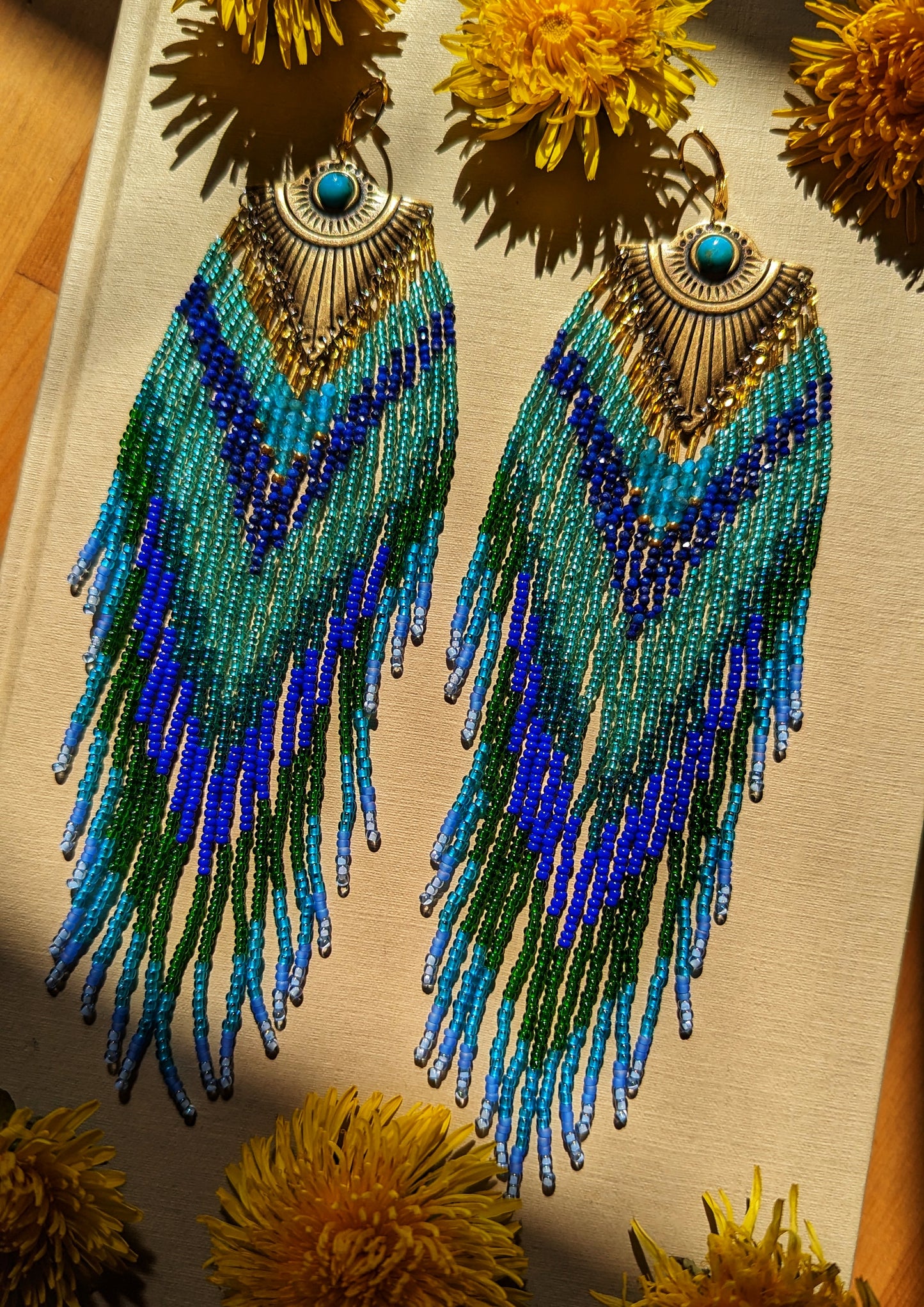 Handcrafted beaded earrings by Moon & Milk inspired by Huitzilopochtli, featuring apatite, lapis lazuli stones, and turquoise cabochons, designed to mimic a hummingbird.