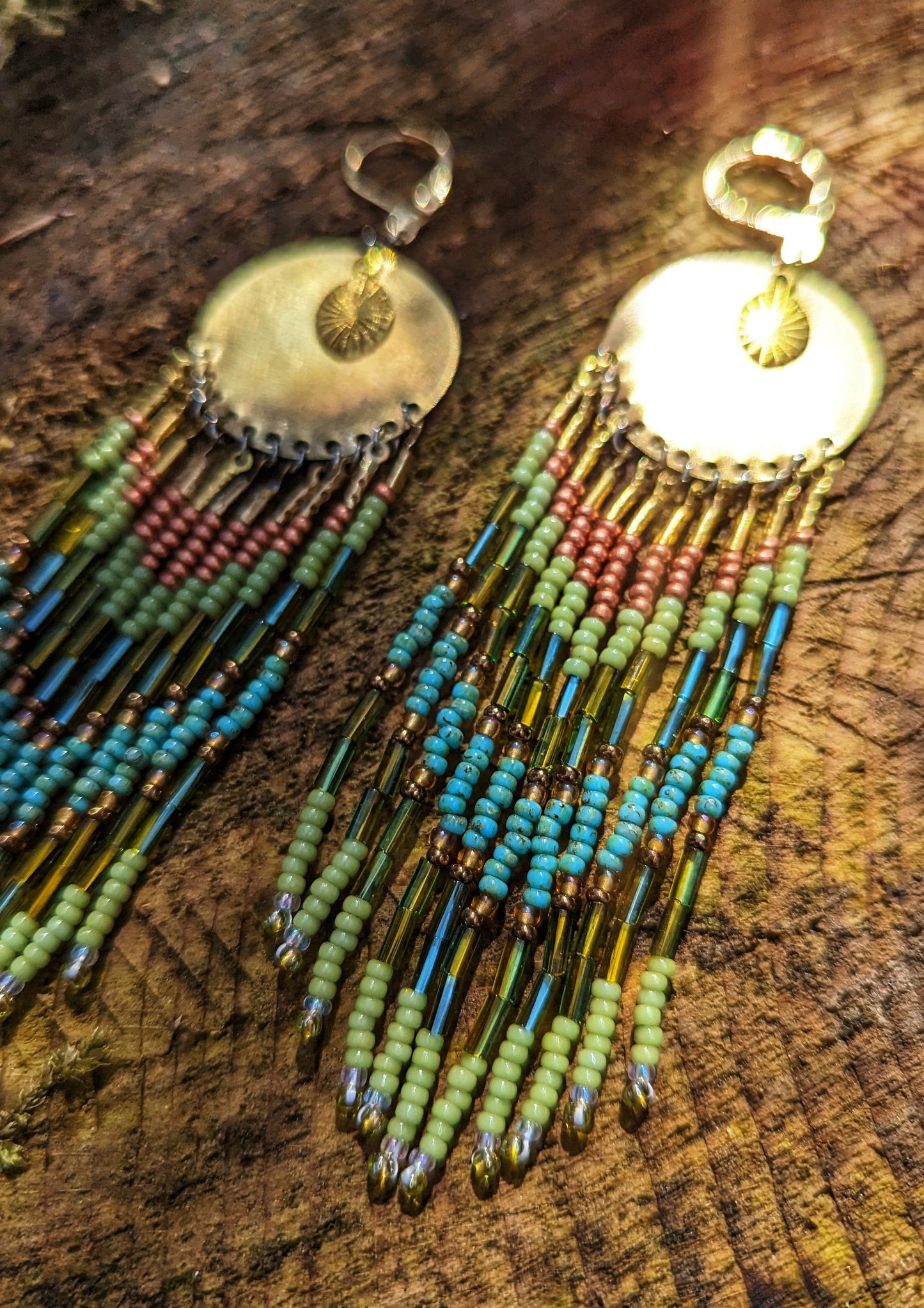 Moon & Milk handcrafted earrings with brass medallion, lime green, copper, and turquoise beaded fringe, inspired by the colors of the rainforest.