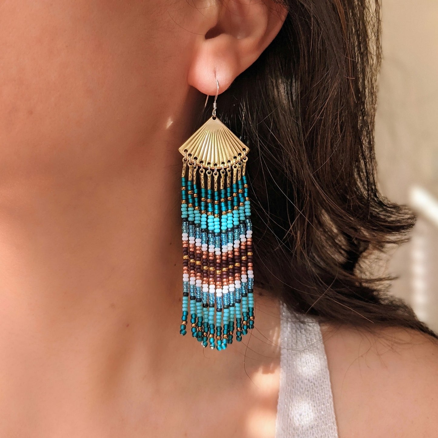 Model wearing Moon & Milk long turquoise, brown, and white beaded earrings with brass fan tops, handmade artisan jewelry with native beadwork influence.