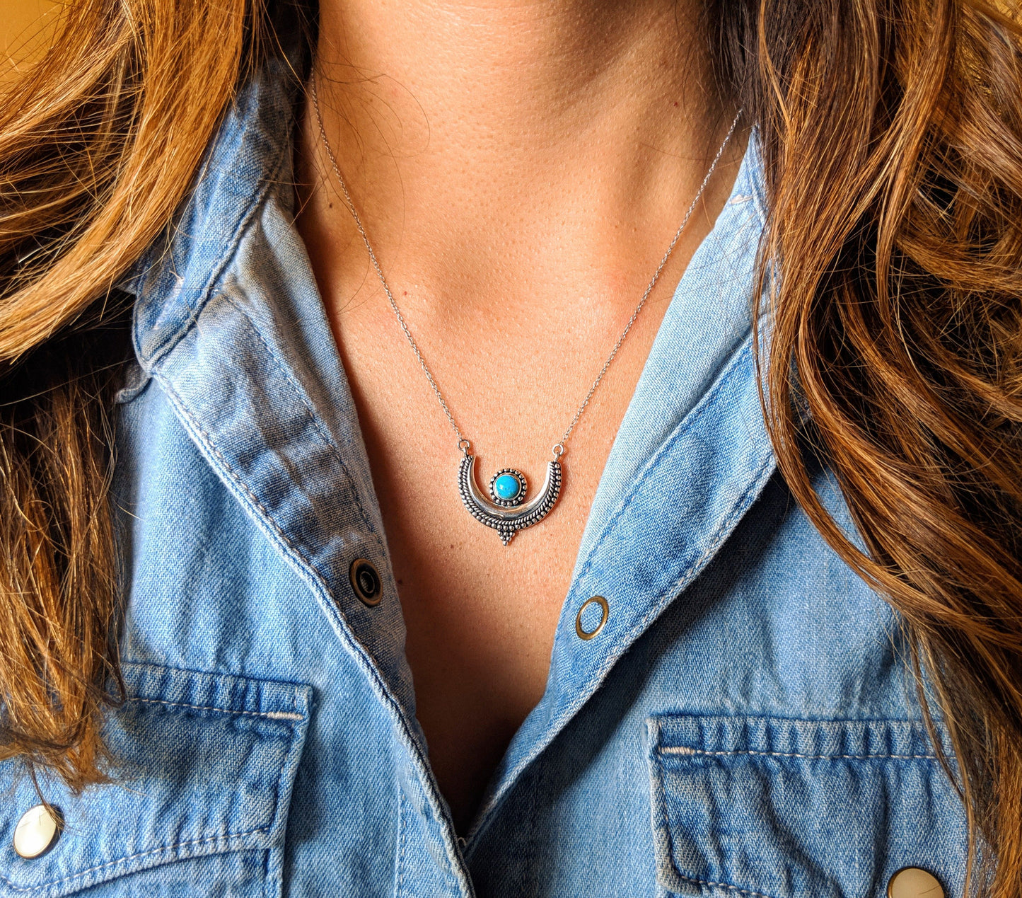 A crescent moon pendant necklace on a model with a round turquoise stone bezel setting and a silver chain. -Moon & Milk