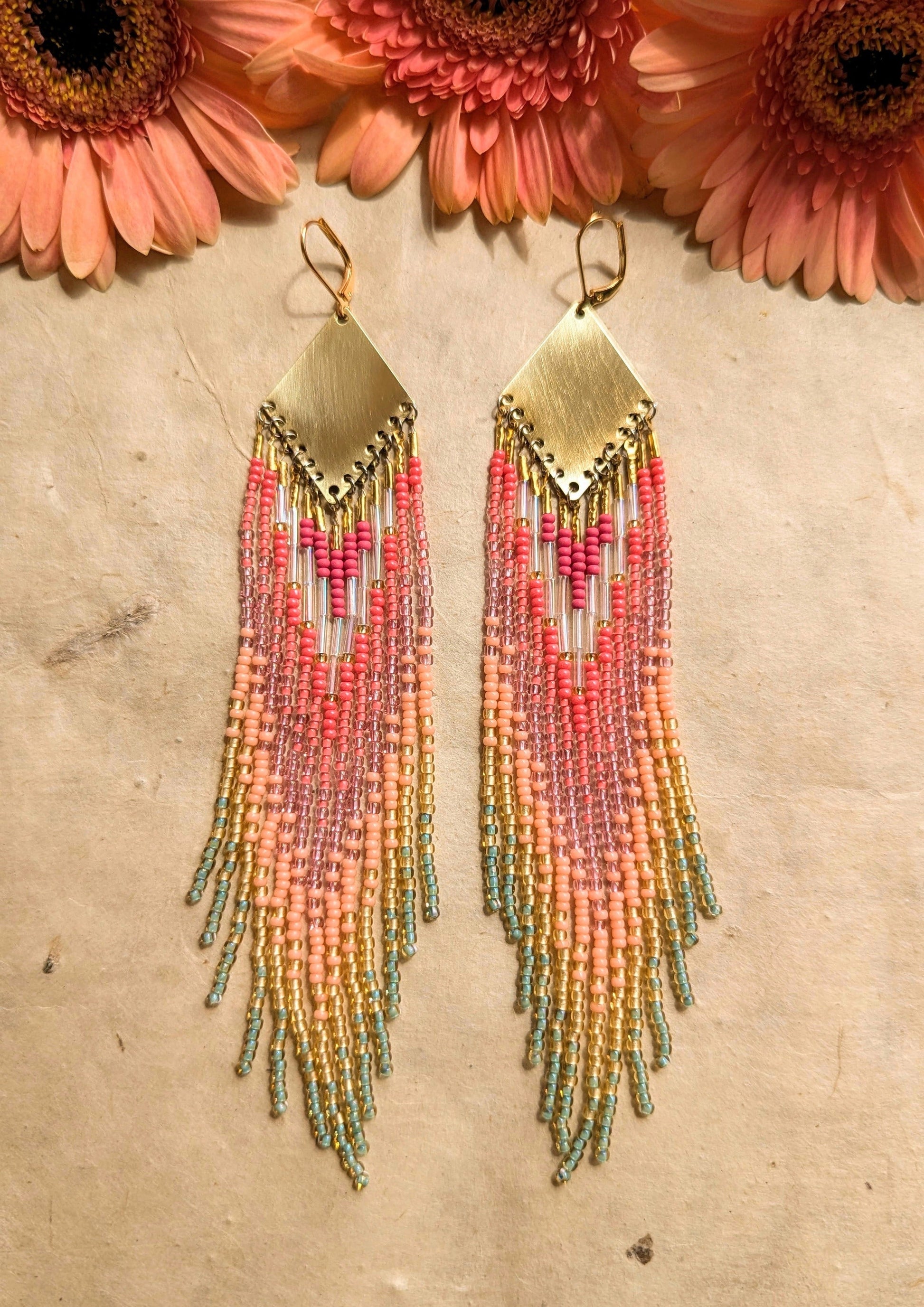 Moon & Milk - Vibrant handmade beaded earrings featuring a blend of pink, peach, and mint green hues, cascading from a brass diamond plate, set against a natural background with soft pink flowers.