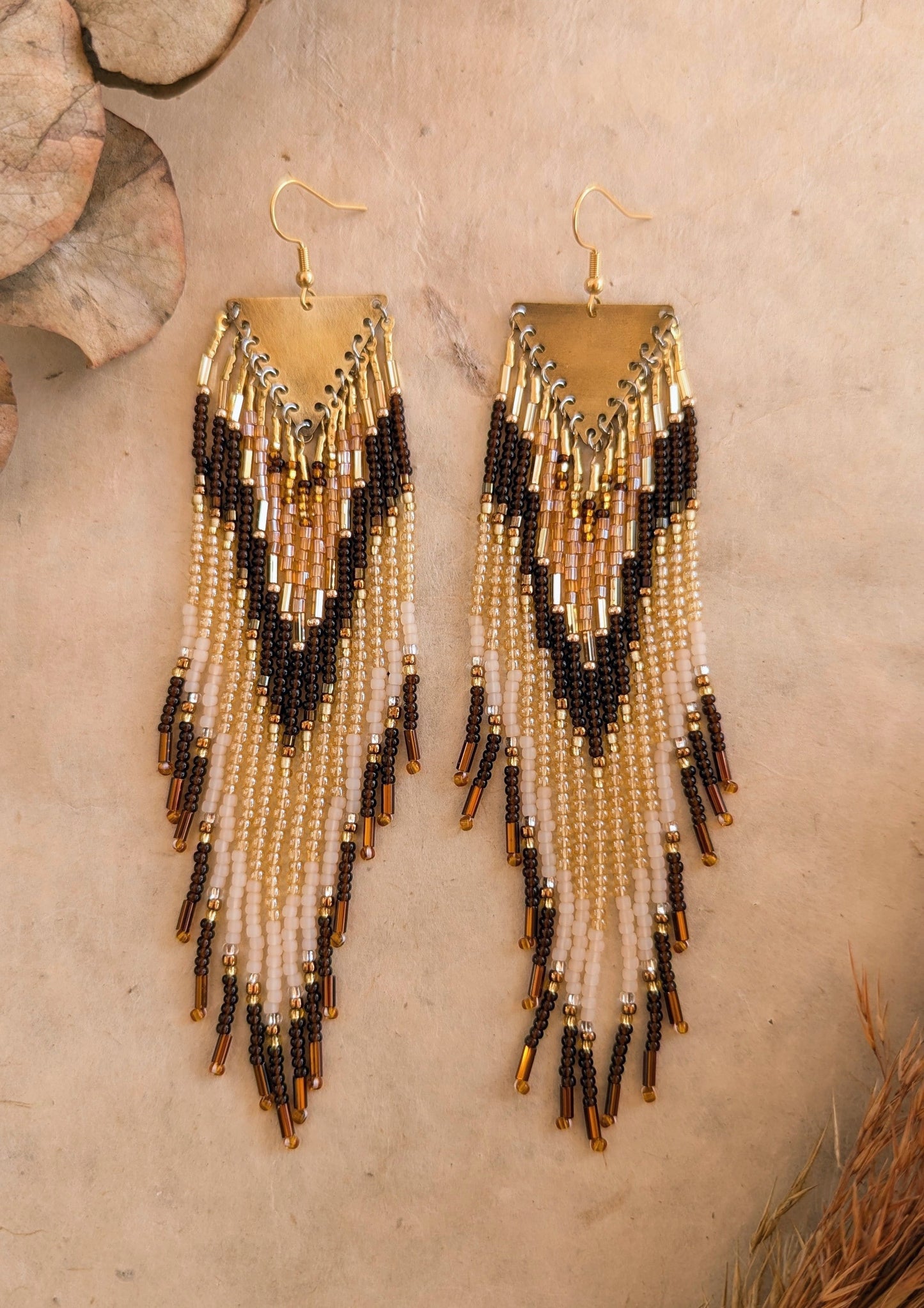 Moon & Milk - Handmade earrings with long brown, gold, and beige bead fringe hanging from a brass plate, creating an earthy and bold design.