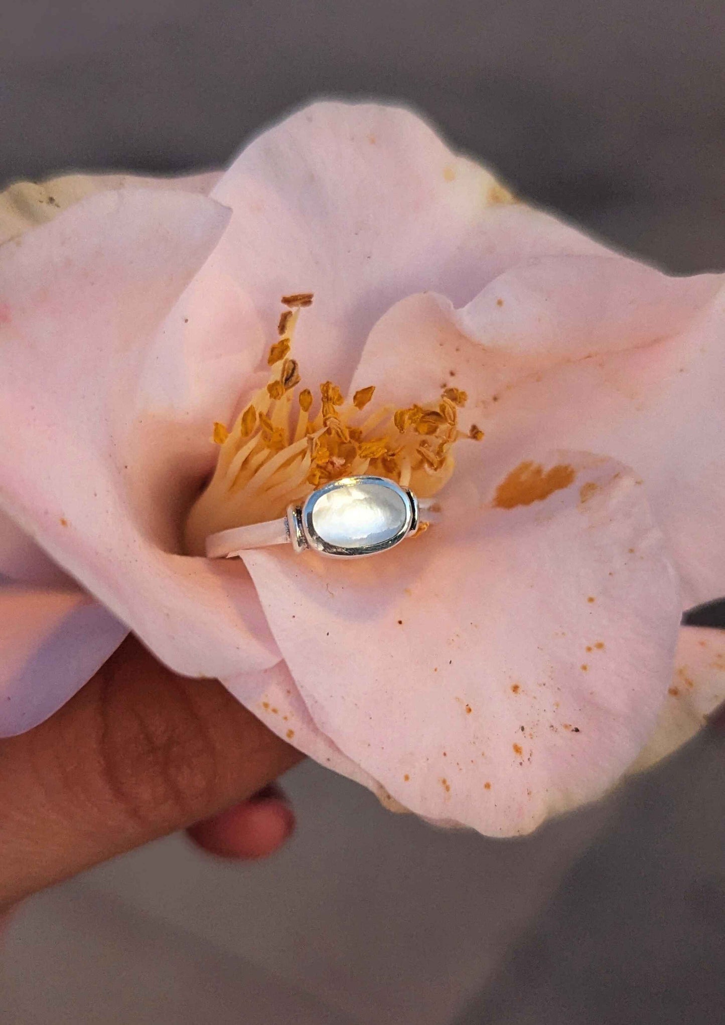 Ring with a large gemstone held inside a pink flower petal.