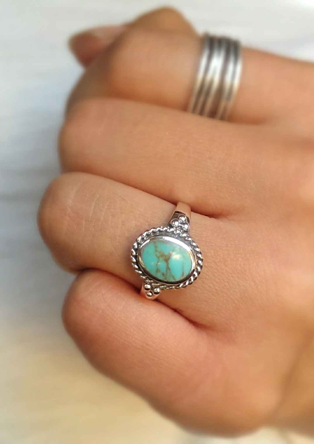 Turquoise stone ring on a finger with a blurred background