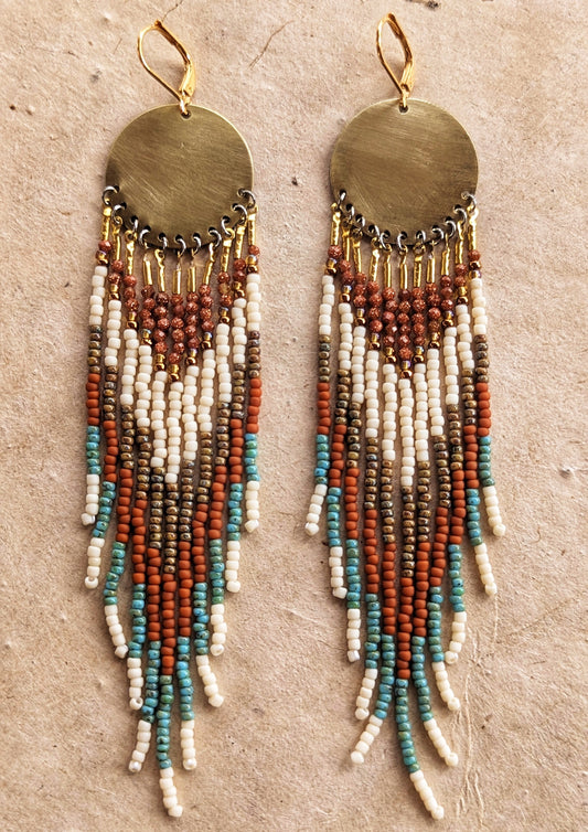Gold dangling beaded earrings with earthy-toned beads in white, brown, and turquoise. Large circular brass discs at the top. Handcrafted by Moon & Milk.