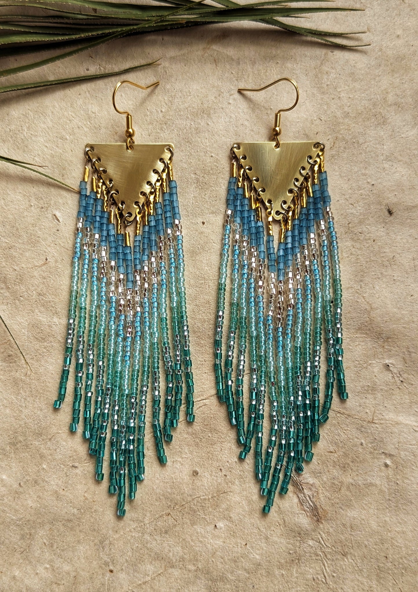 Moon & Milk - Handmade boho beaded earrings with blue and green cascading strands, accented with gold triangular pendants.