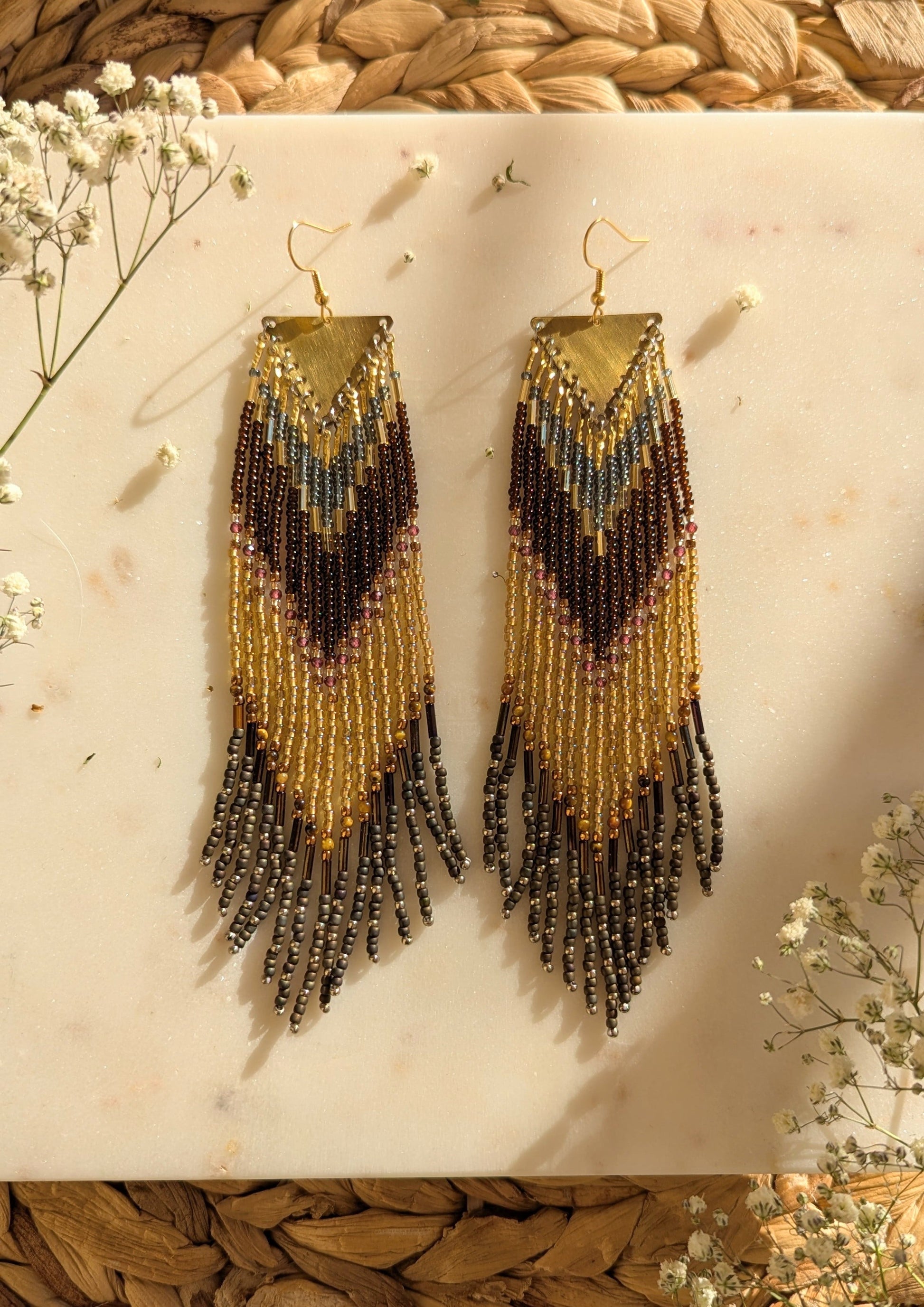 Chevron-patterned beaded earrings in gold, brown, and rustic tones with fringe details, handcrafted for a boho-chic and elegant statement.