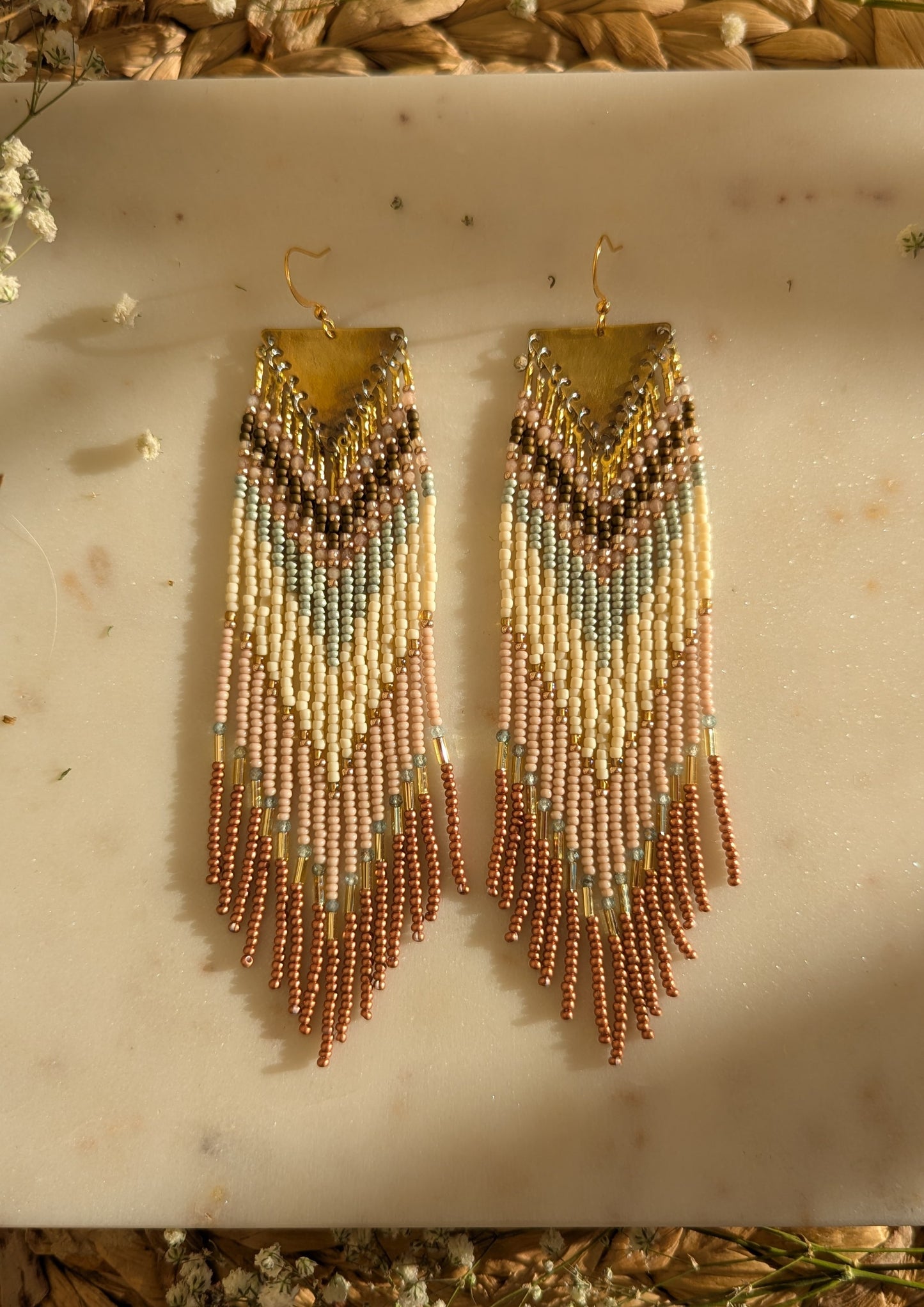 Delicate beaded fringe earrings with pastel tones of cream, blush, and mint green in a chevron pattern, finished with shimmering bronze fringe accents.