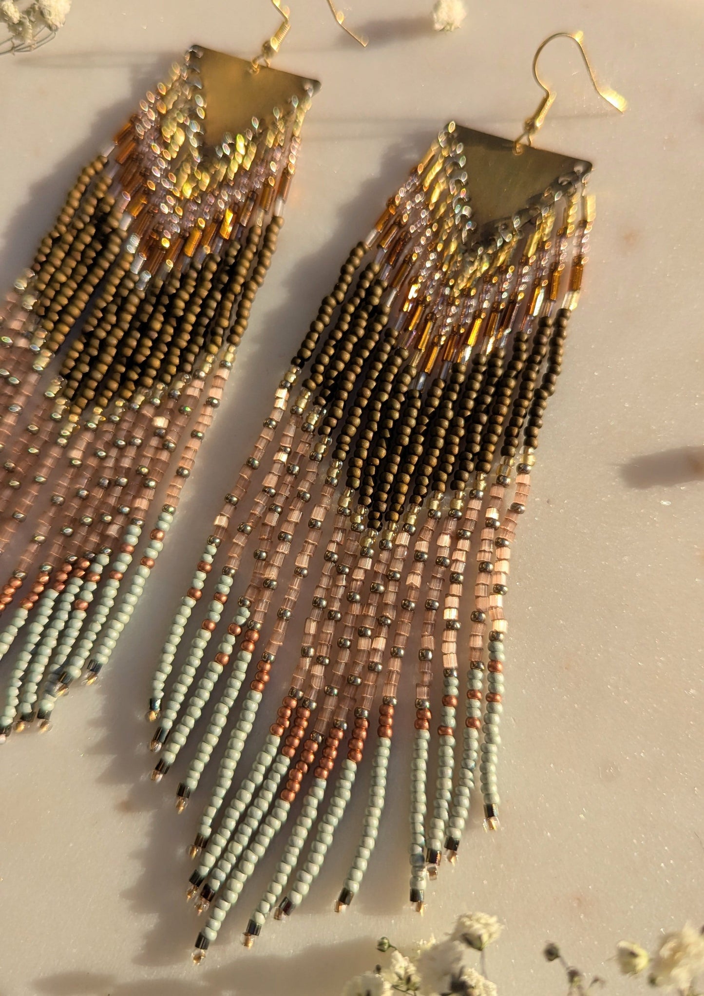 Handcrafted beaded fringe earrings with a chevron pattern in gold, bronze, and mint green, accented by delicate fringe and shimmering details.