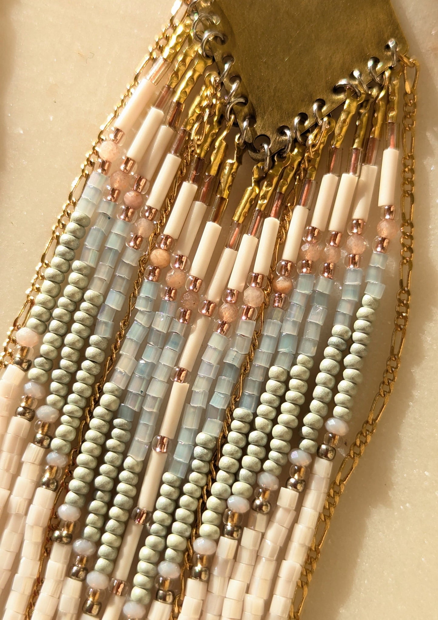 Handcrafted beaded fringe earrings featuring a chevron pattern in pastel blue, ivory, and gold, with cascading beaded fringes for a bohemian-inspired look.