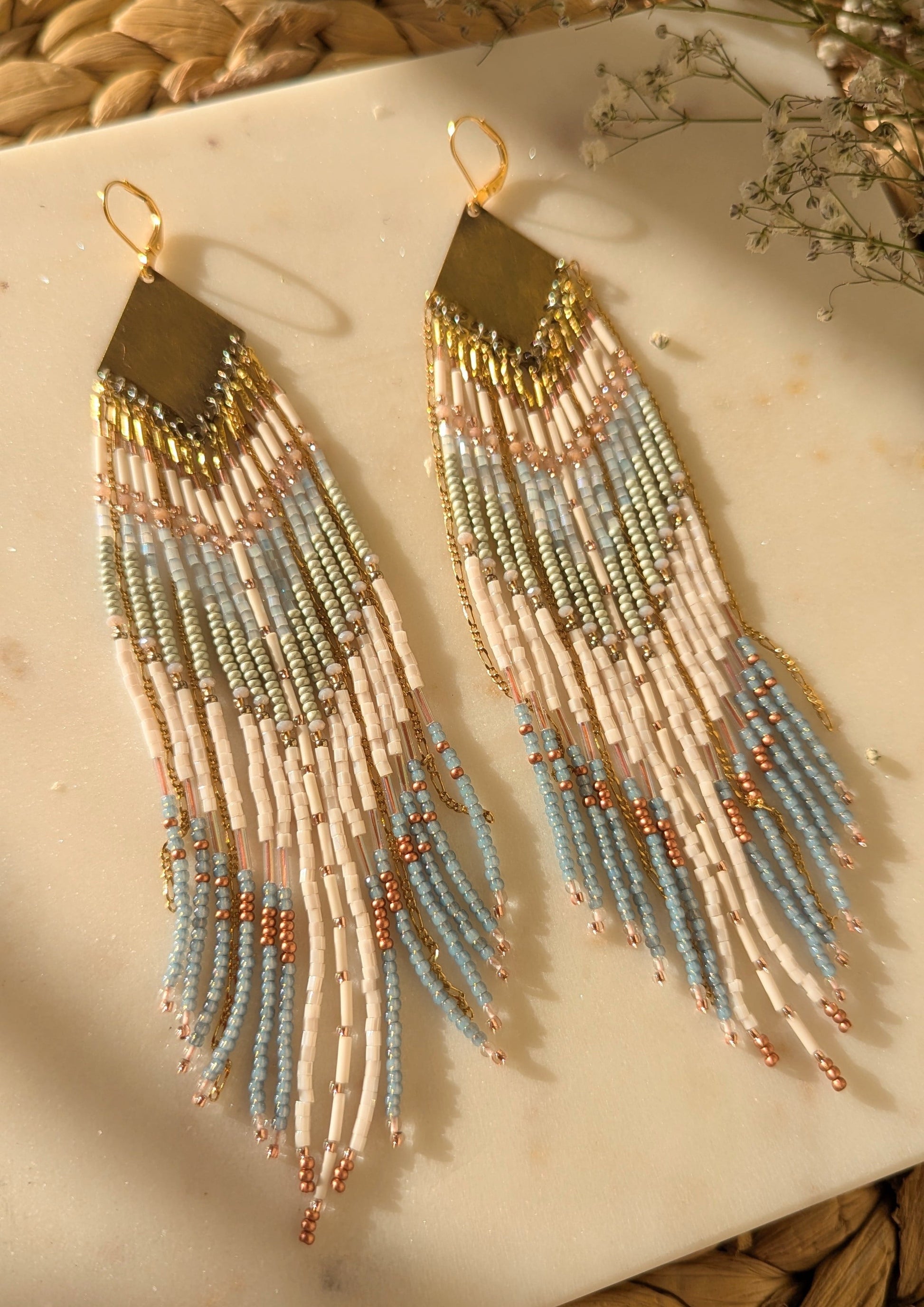 Handcrafted beaded fringe earrings featuring a chevron pattern in pastel blue, ivory, and gold, with cascading beaded fringes for a bohemian-inspired look.