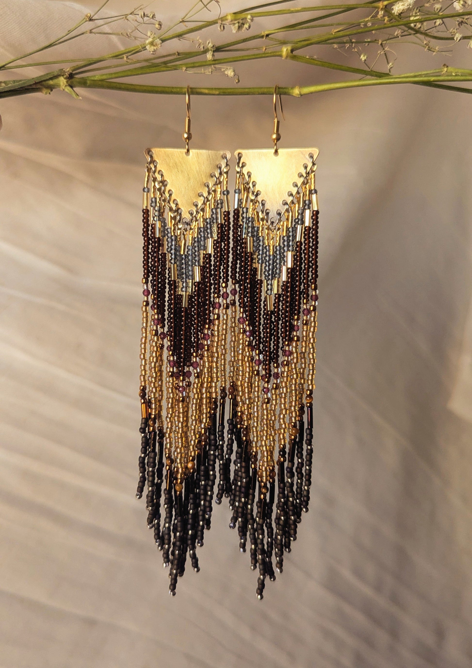 Hand-beaded earrings featuring chevron patterns in gold, olive green, and blue tones with cascading fringes.