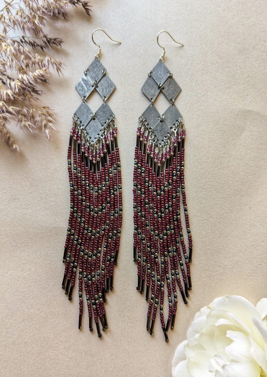 Handcrafted beaded earrings with geometric silver accents, burgundy beads, and intricate fringe design, perfect for boho or evening wear styles.