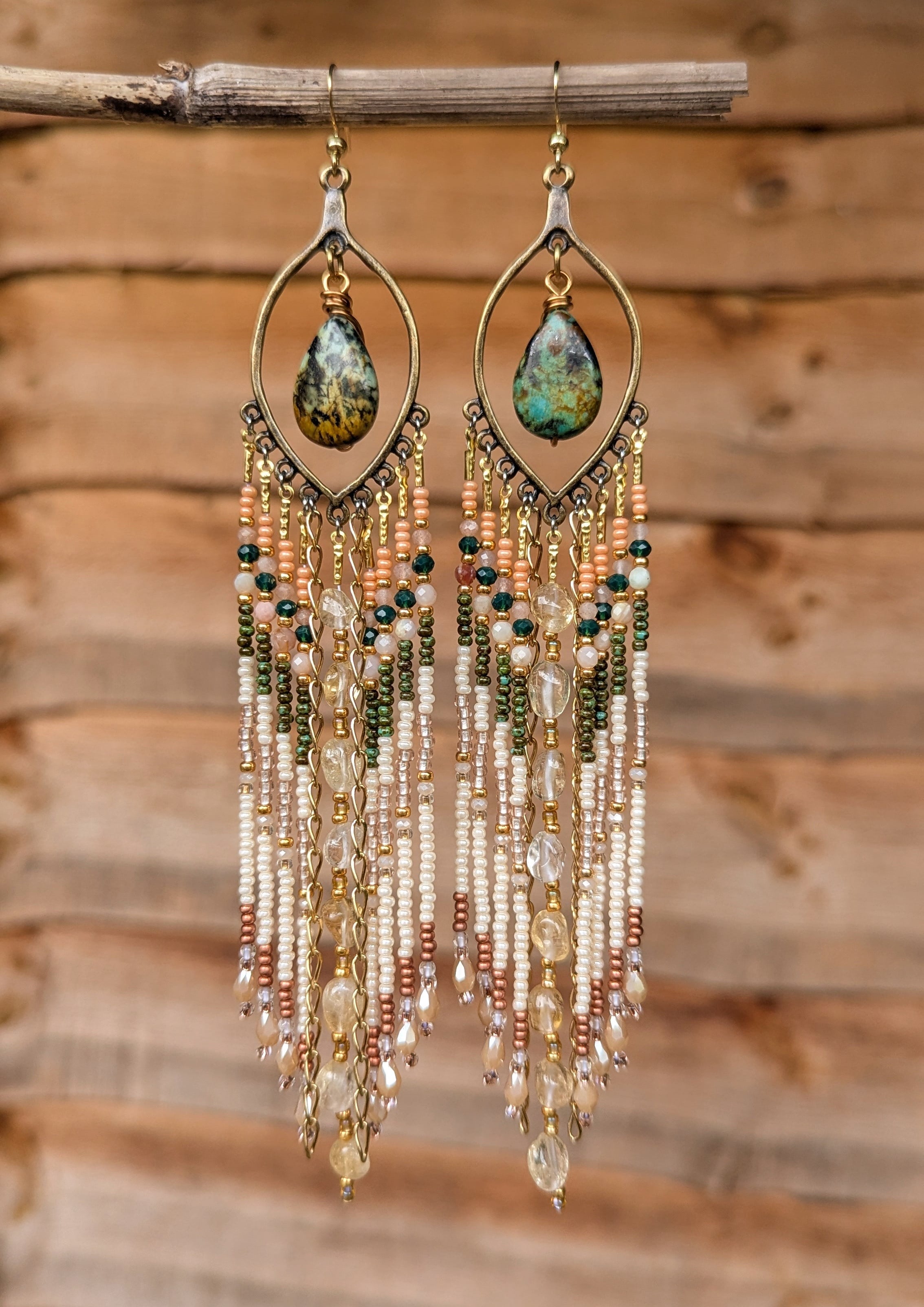 Delicate beaded earrings with teardrop-shaped gemstones on a wooden background