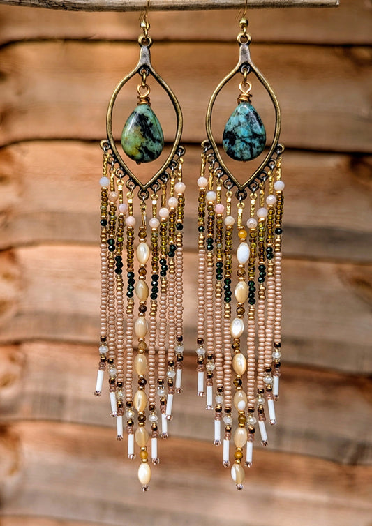 Hand-beaded earrings with turquoise stones on a wooden background.