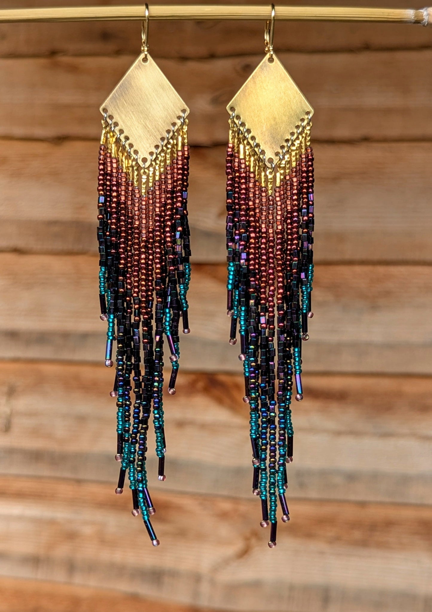 Hand-beaded earrings with a gradient of colors on a wooden background by Moon & Milk.