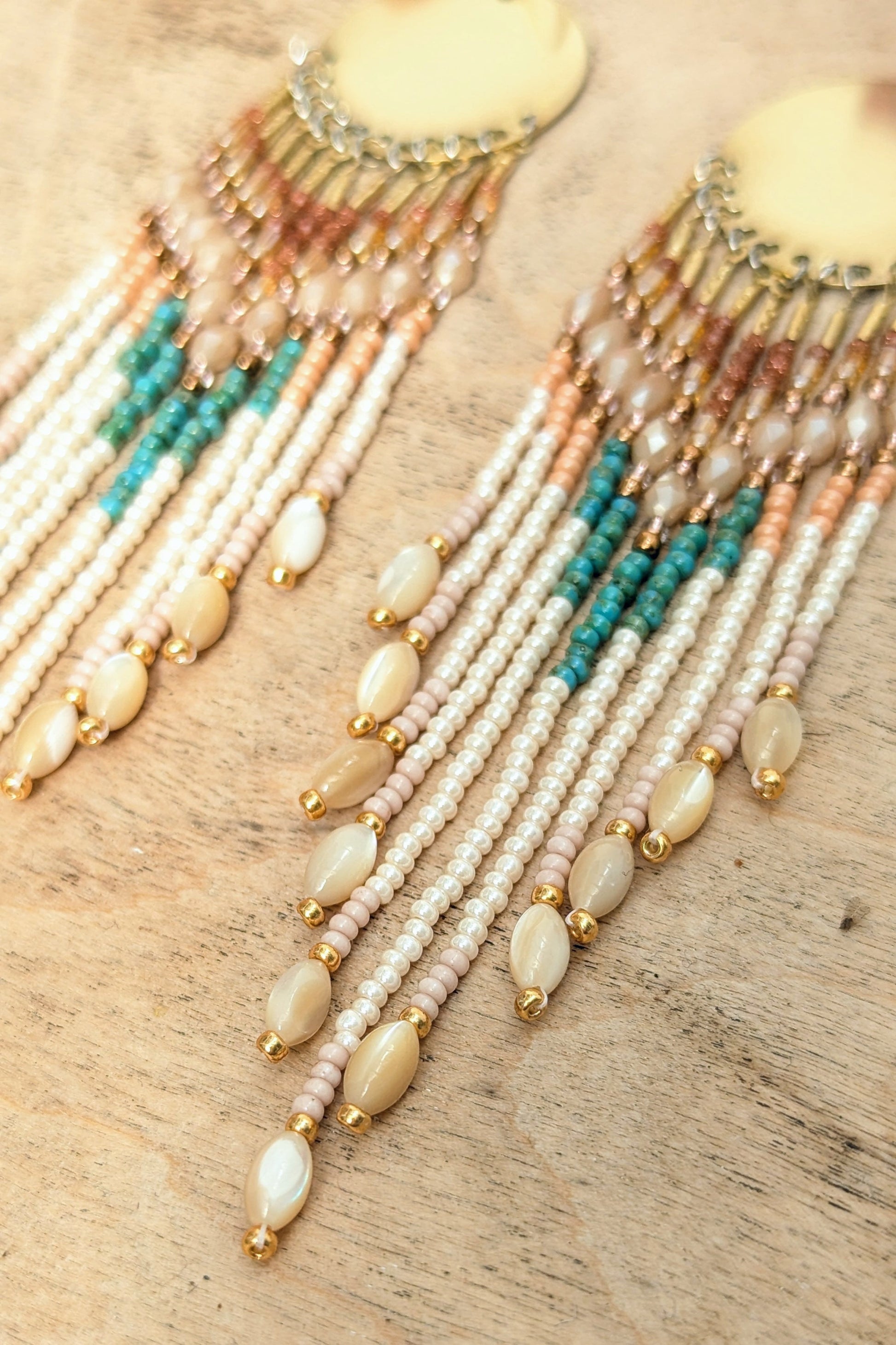 Beaded boho earrings with turquoise and gold accents on a wooden surface by Moon & Milk.