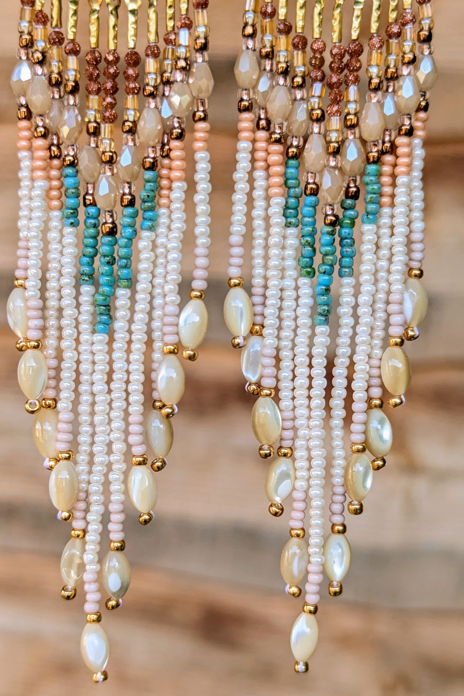 Multicolored handcrafted beaded earrings with pearls on a blurred background.