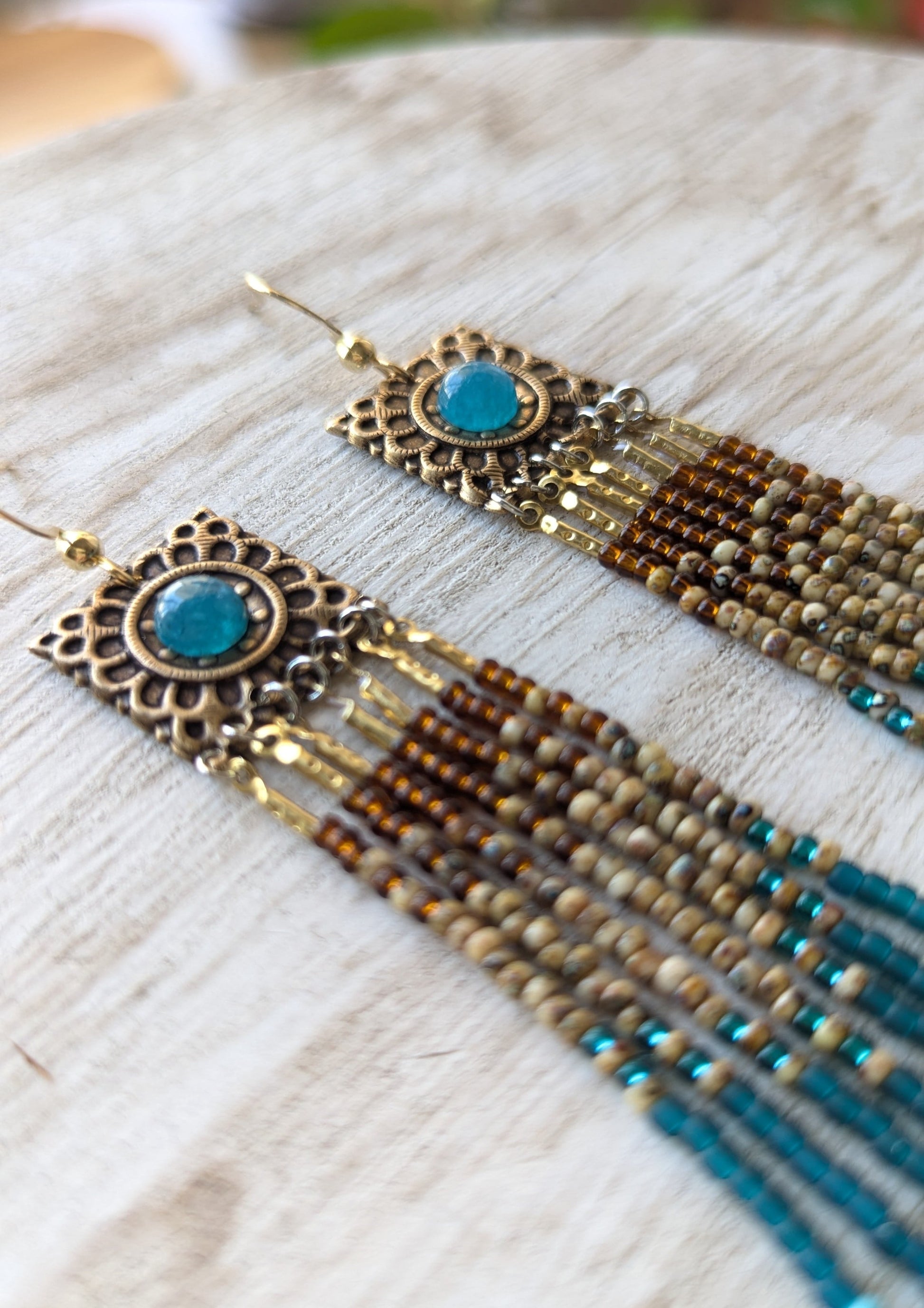 Pair of beaded earrings with apatite stones on a textured surface.