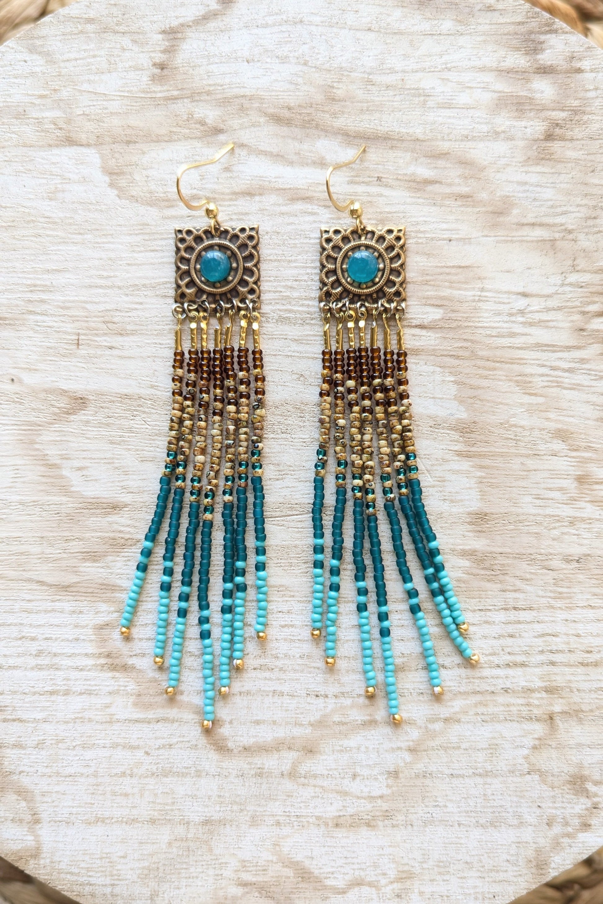 Turquoise beaded earrings on a wooden surface.