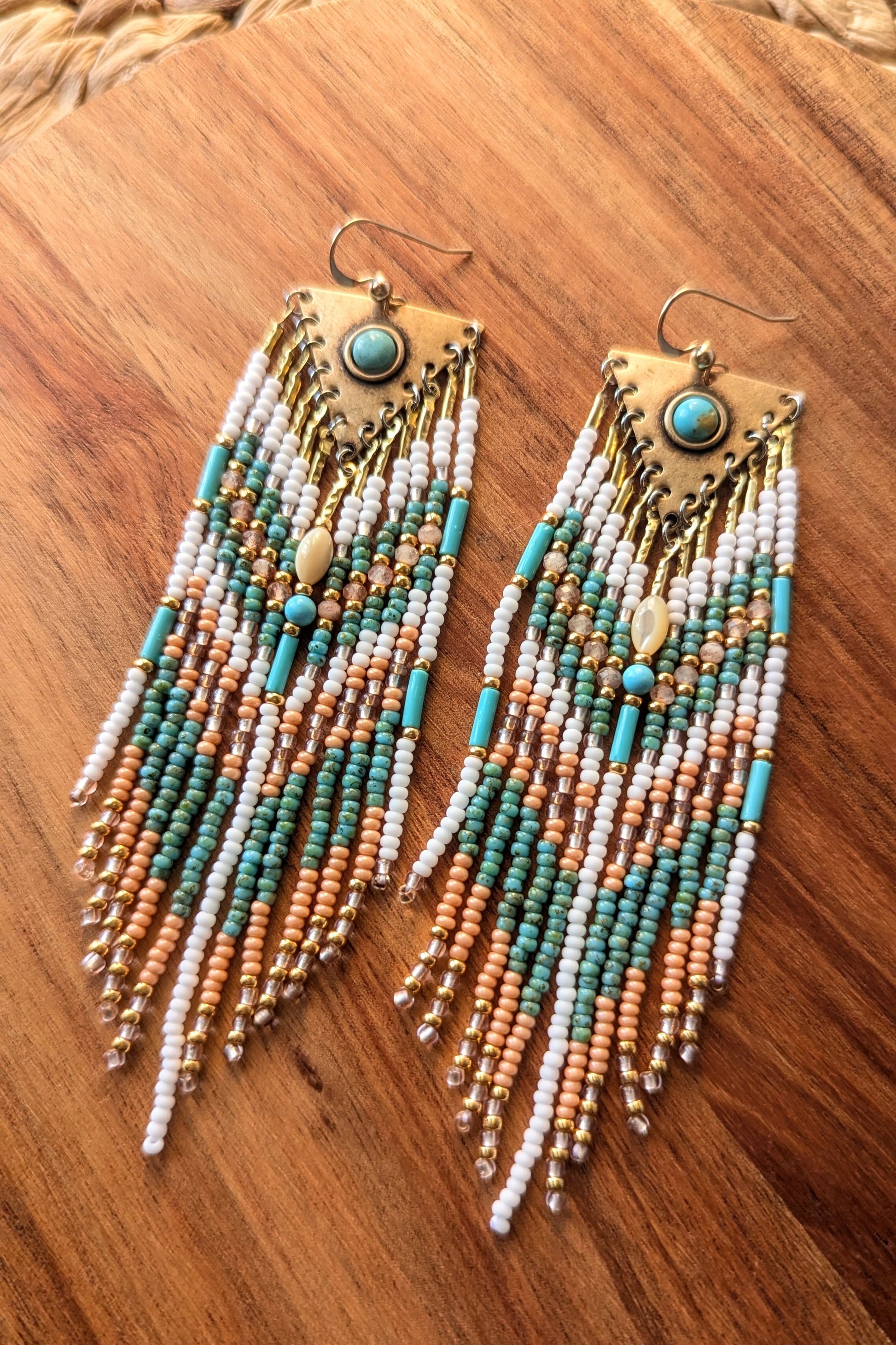 Beaded earrings with turquoise and gold accents on a wooden surface by Moon & Milk.