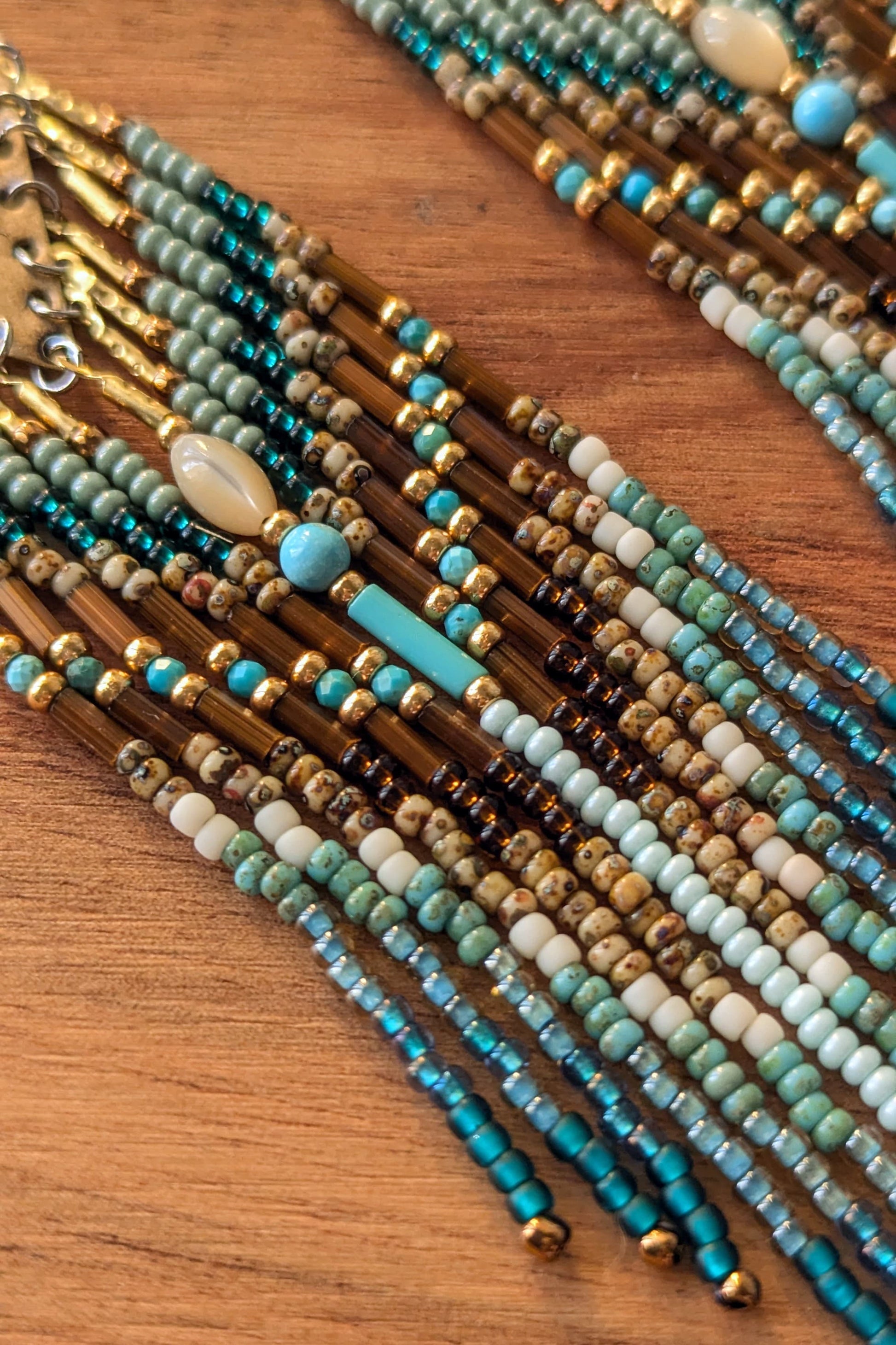 Close-up of beaded teal earrings in various colors on a wooden surface