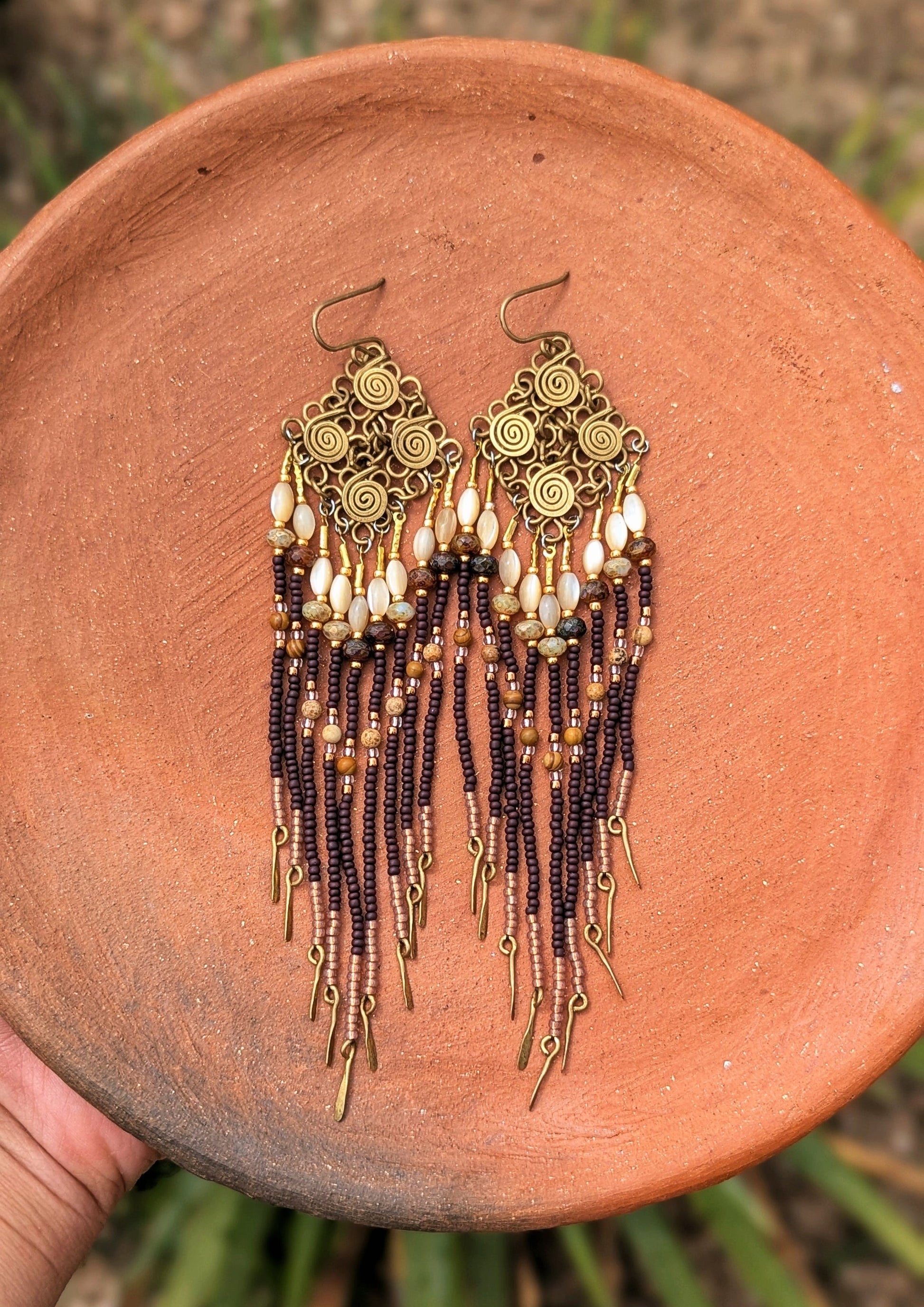 Pair of beaded earrings on a terracotta plate with a natural background