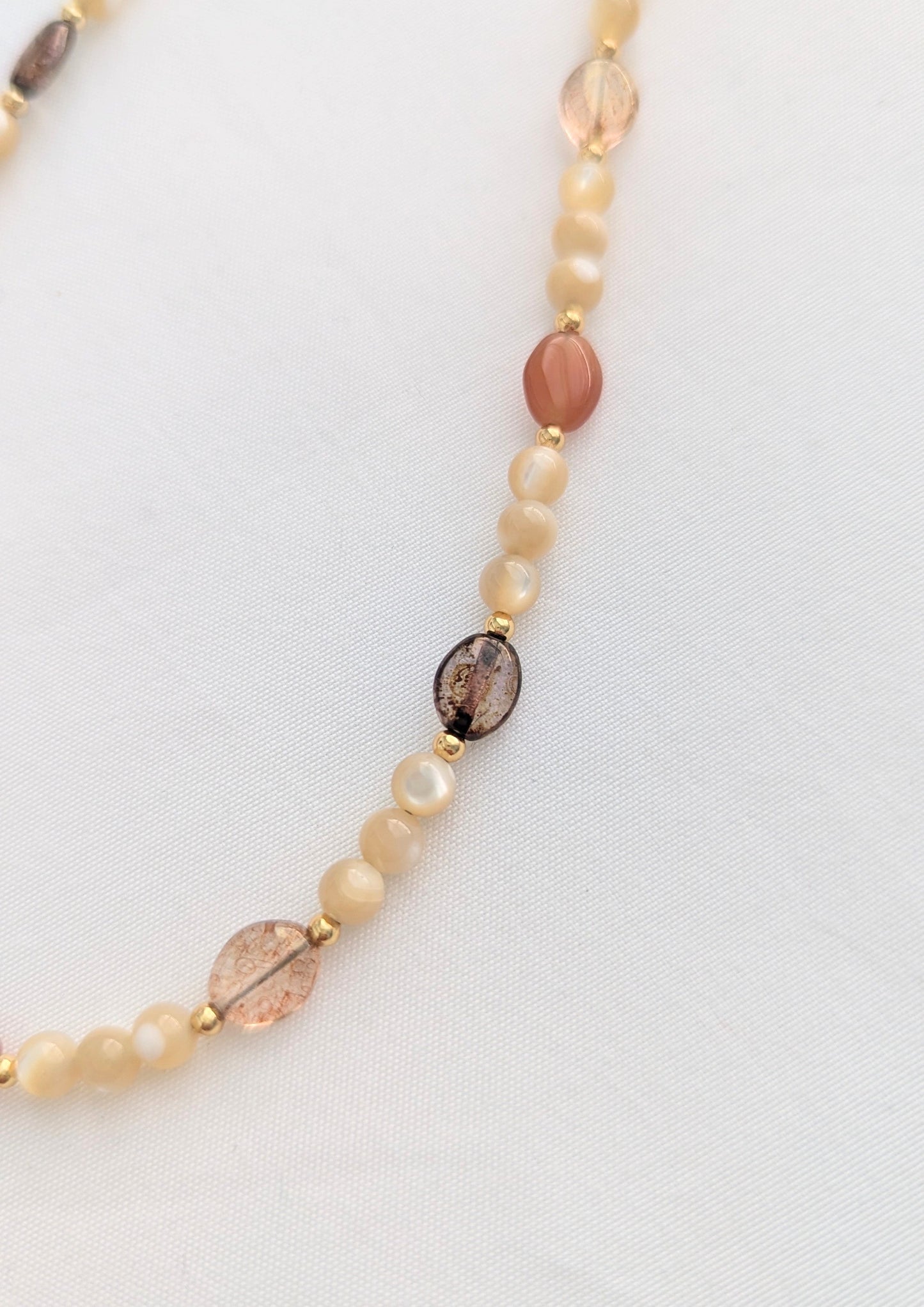 Necklace with pearls and leaf-shaped beads on a white background.