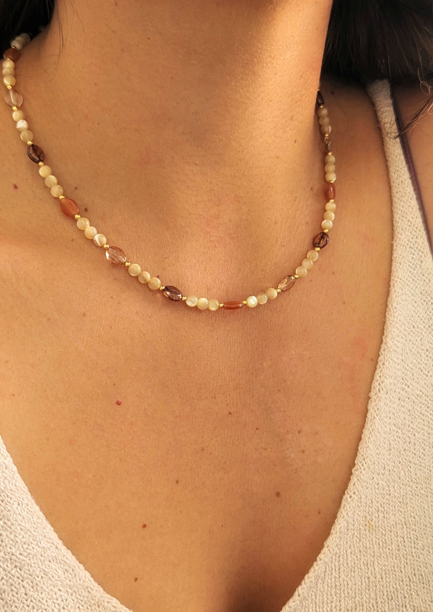Necklace made with mother of pearl beads, 18k gold-plated spacer beads, and mixed Czech glass beads in warm neutral tones displayed on a woman.