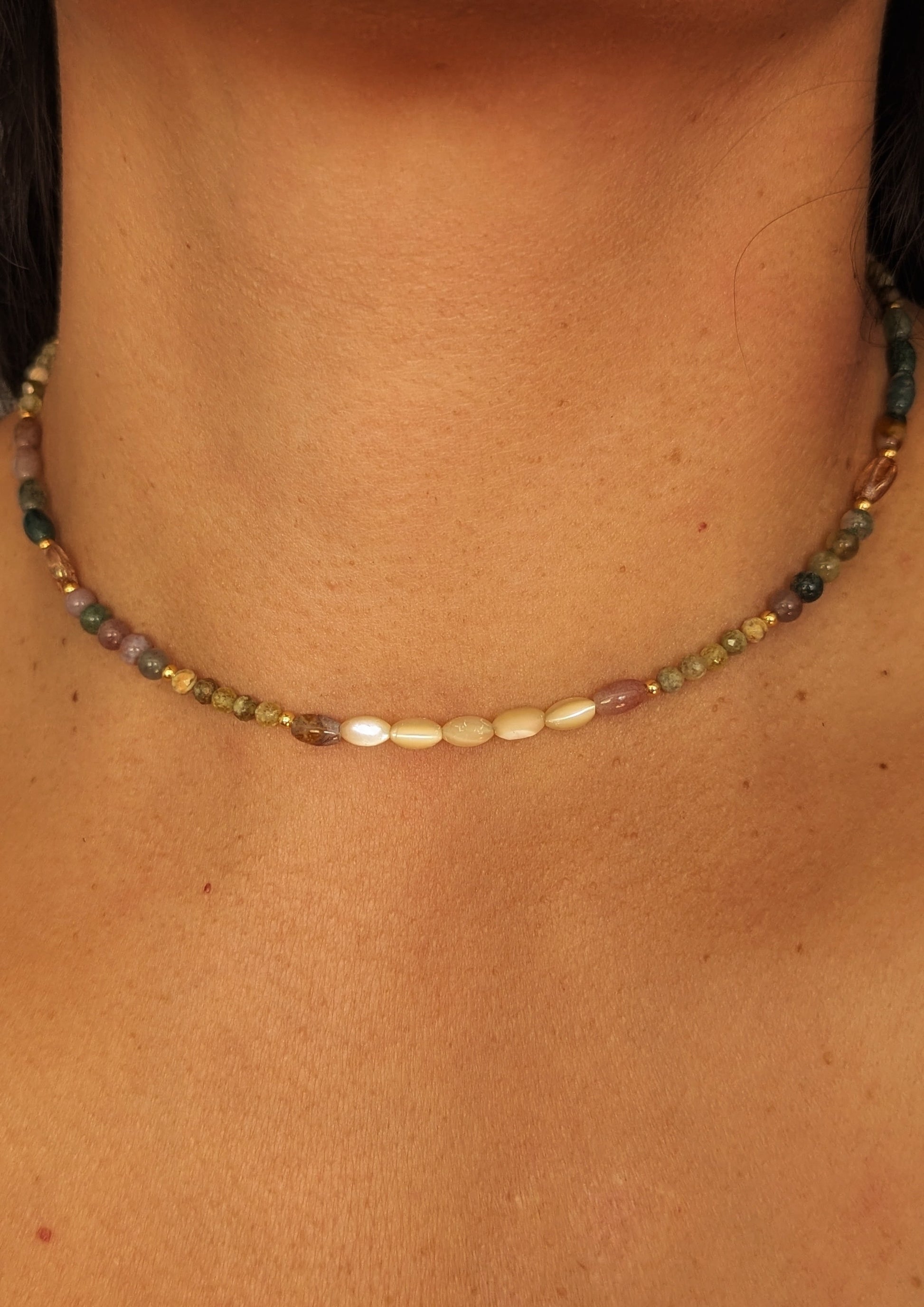 Necklace with multicolored Indian agate and mother-of-pearl beads on a person's neck.