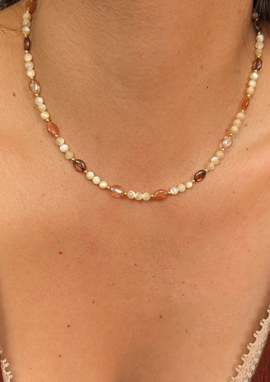 Necklace made with mother of pearl beads, 18k gold-plated spacer beads, and mixed Czech glass beads in warm neutral tones displayed on a woman.