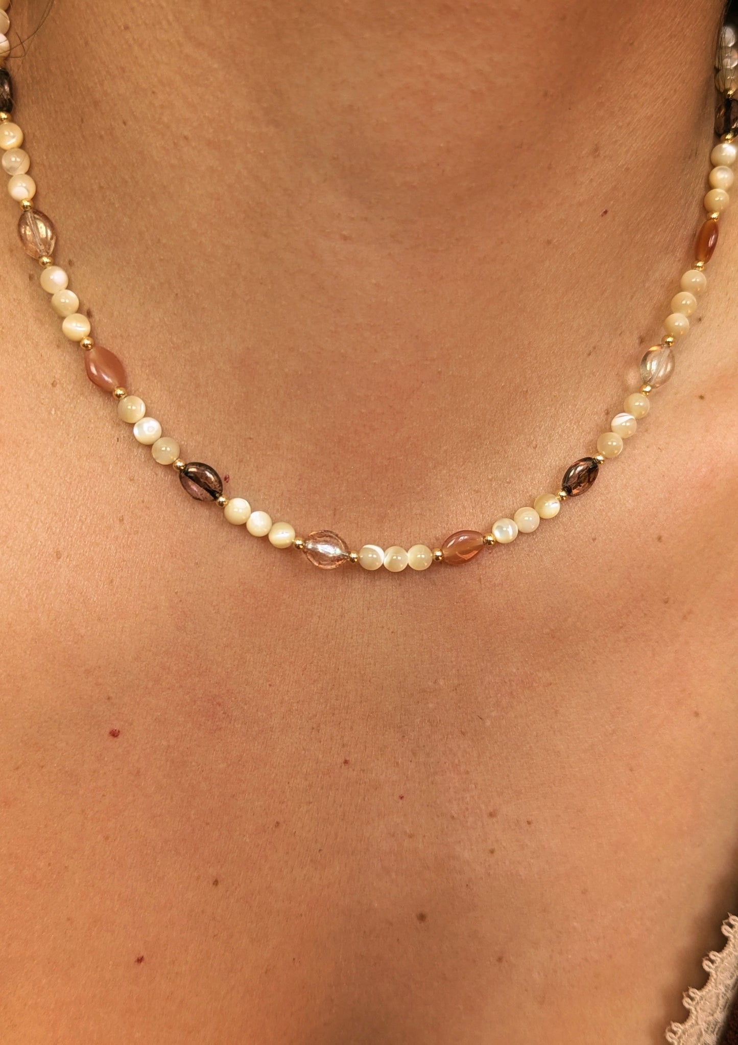 Necklace made with mother of pearl beads, 18k gold-plated spacer beads, and mixed Czech glass beads in warm neutral tones displayed on a woman.