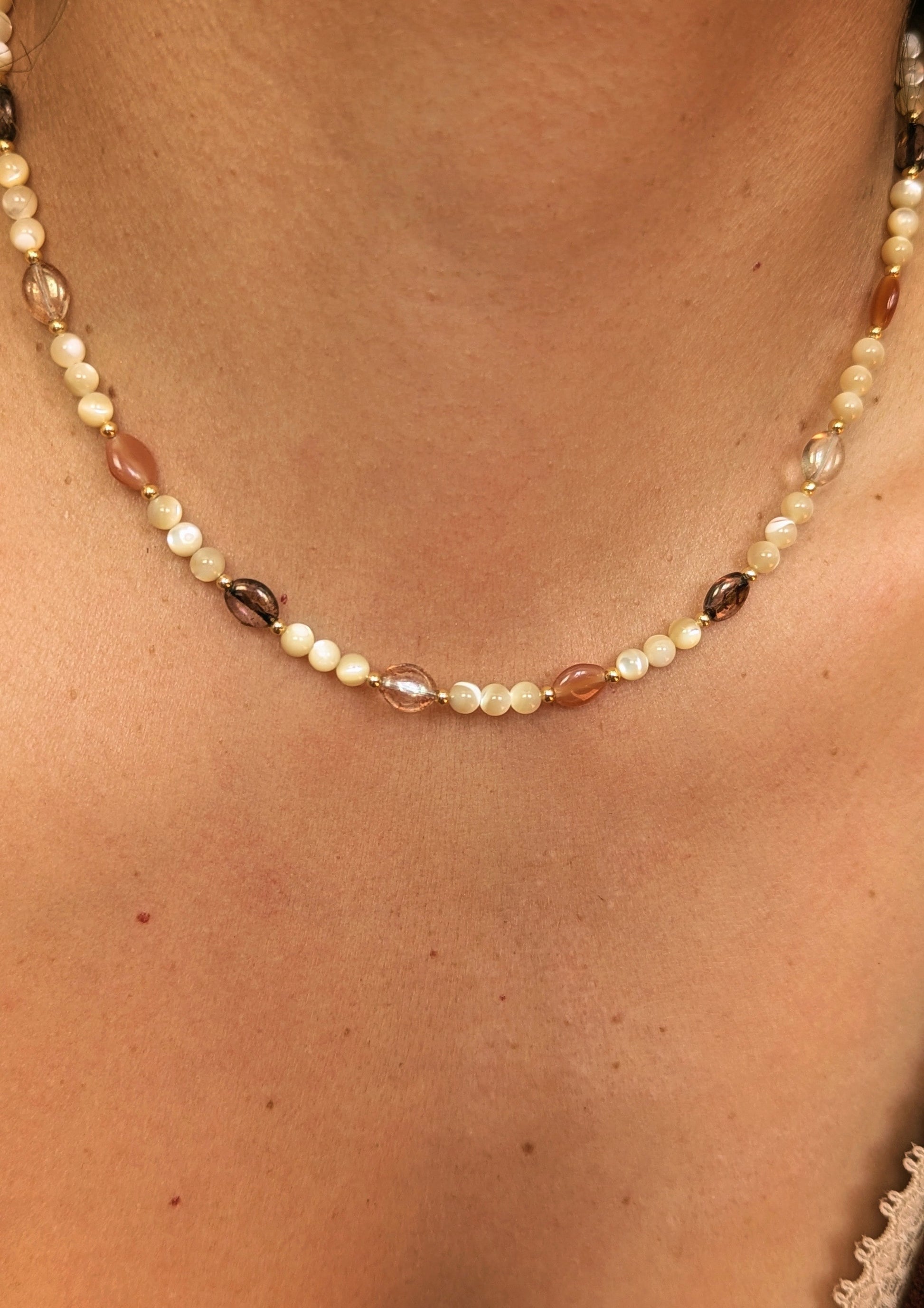 Necklace made with mother of pearl beads, 18k gold-plated spacer beads, and mixed Czech glass beads in warm neutral tones displayed on a woman.